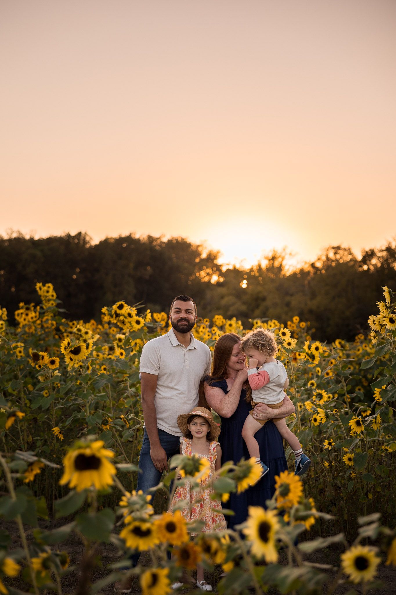 Family of four posing in a sunflower field at golden hour sunset at Jersey Acres Farm in Medford, Burlington County, NJ