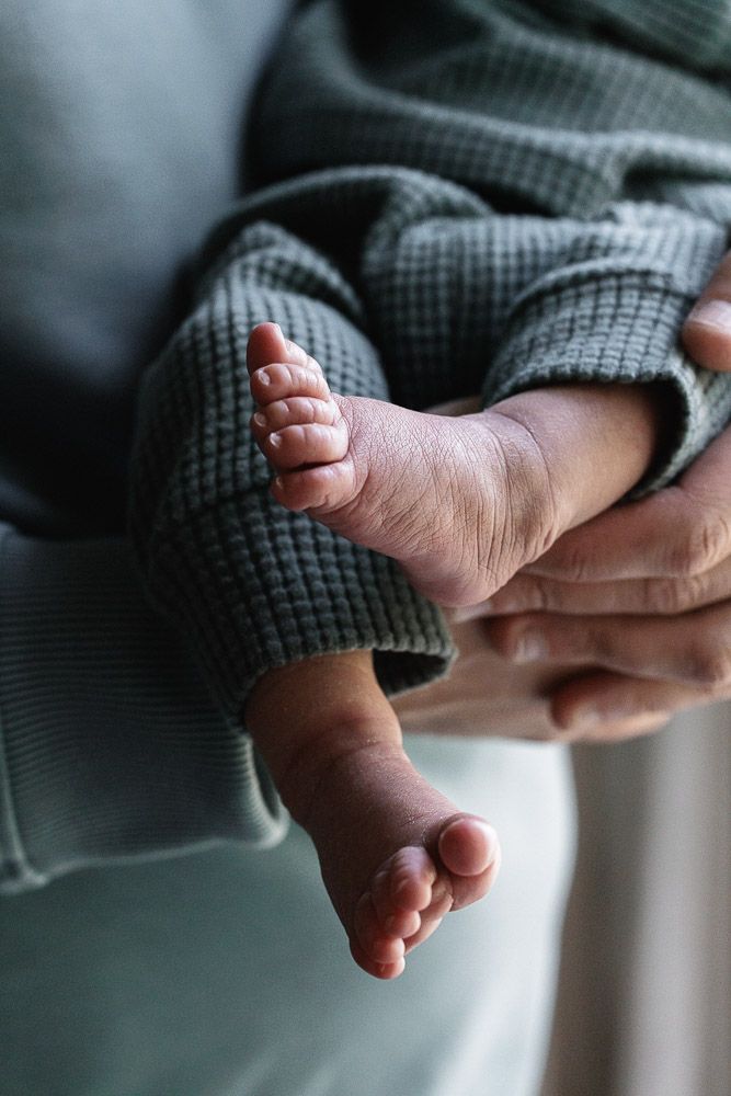 Close-up series of a tiny baby foot wrapped in a gray knit blanket showing different angles in soft lighting.