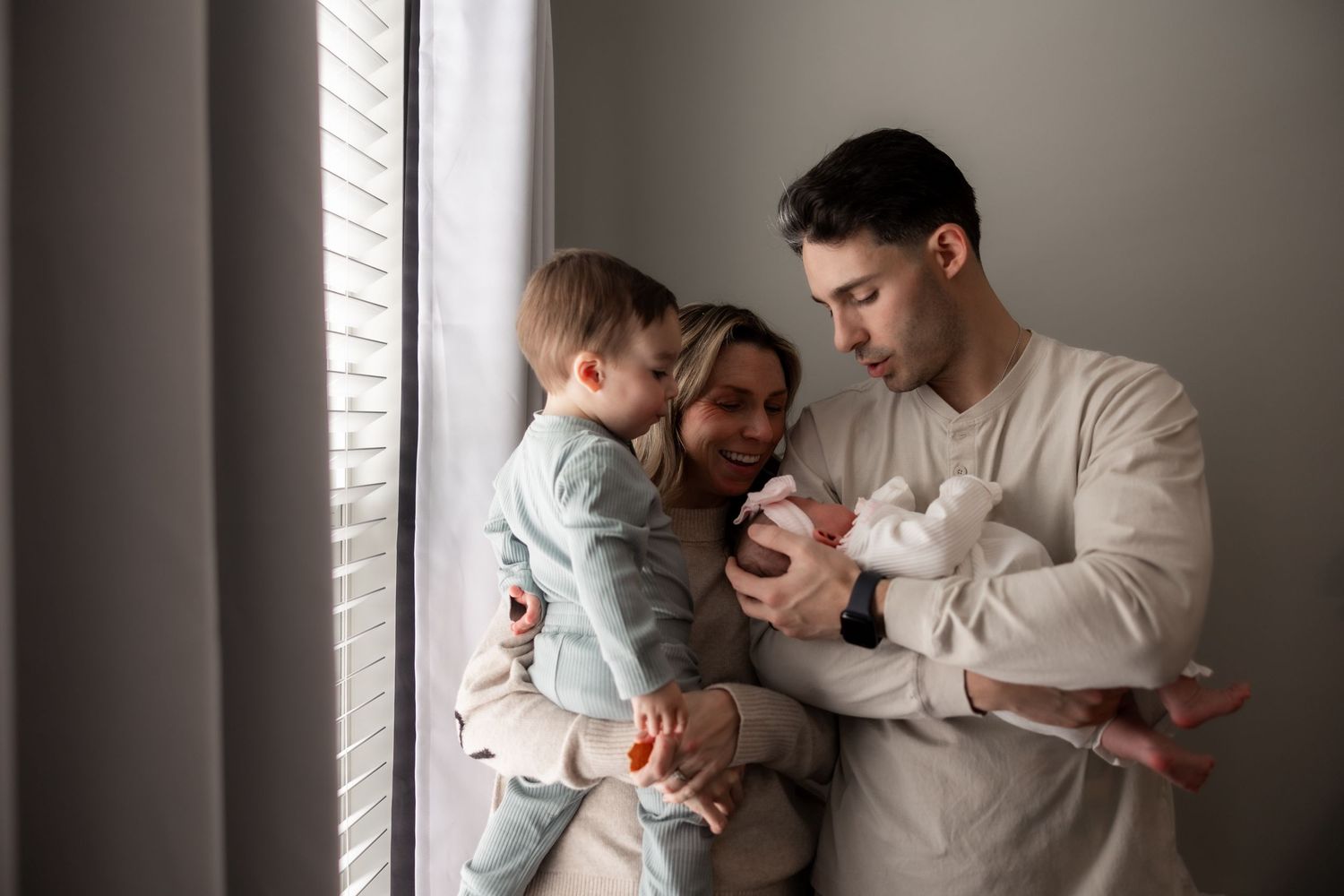 Parents and toddler holding newborn baby during lifestyle newborn session in Mercer County, New Jersey, by Rego Photography