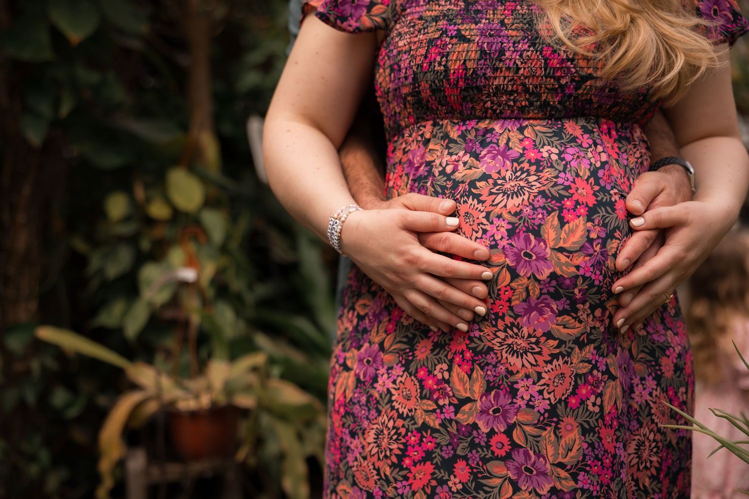 Expectant parents cradling bump during maternity session at a greenhouse in Mercer County, New Jersey, by Rego Photography