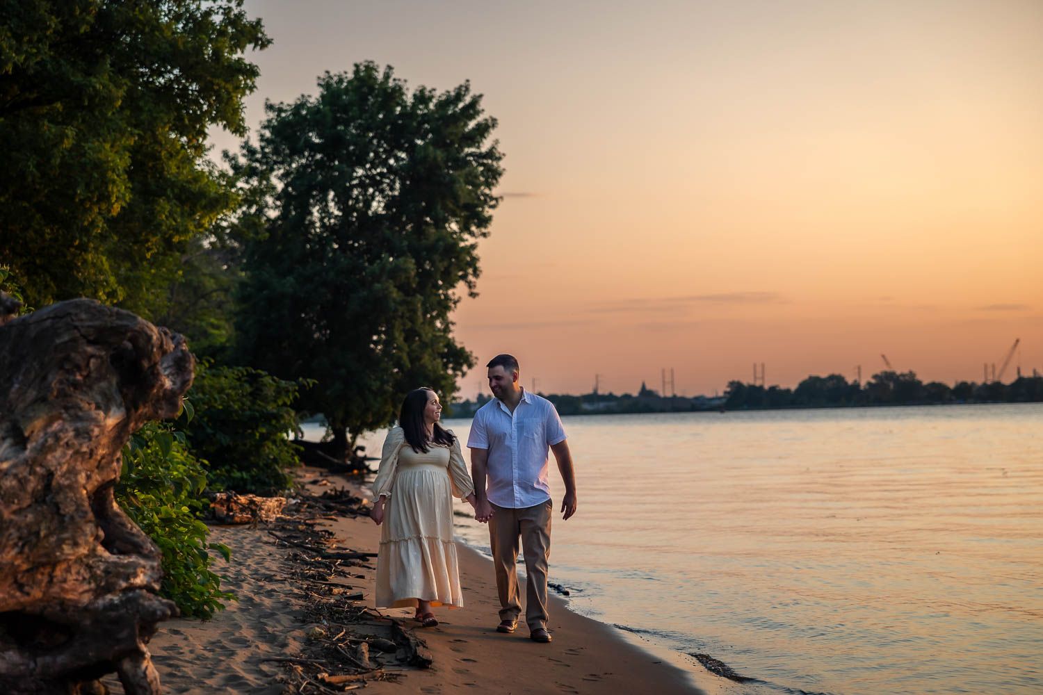 Couple walking alongside the water during golden hour maternity session at Palmyra Nature Cove in Burlington County, NJ