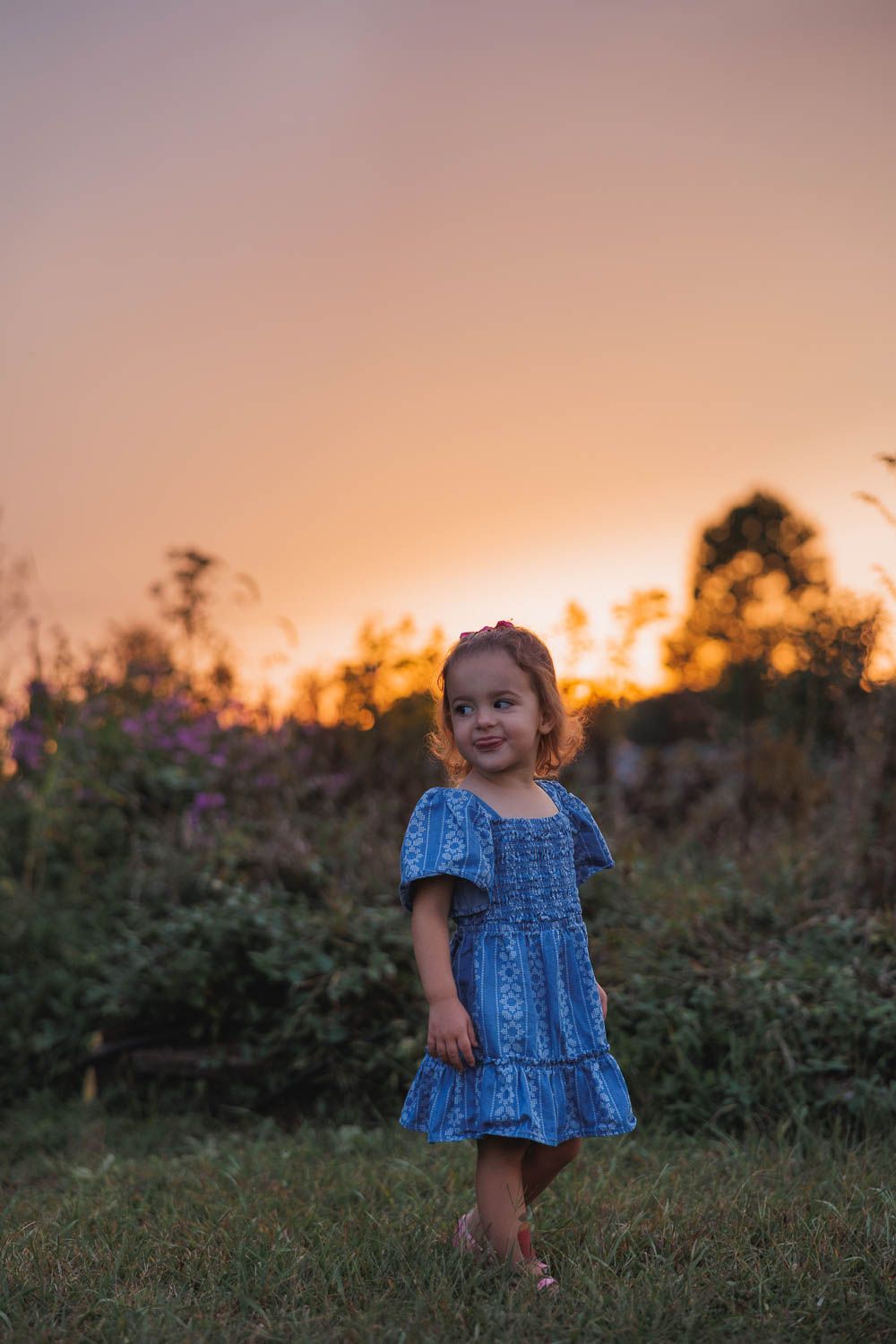 Child posing in front of wildflowers during family photo session at Swedes Run in Moorestown, NJ