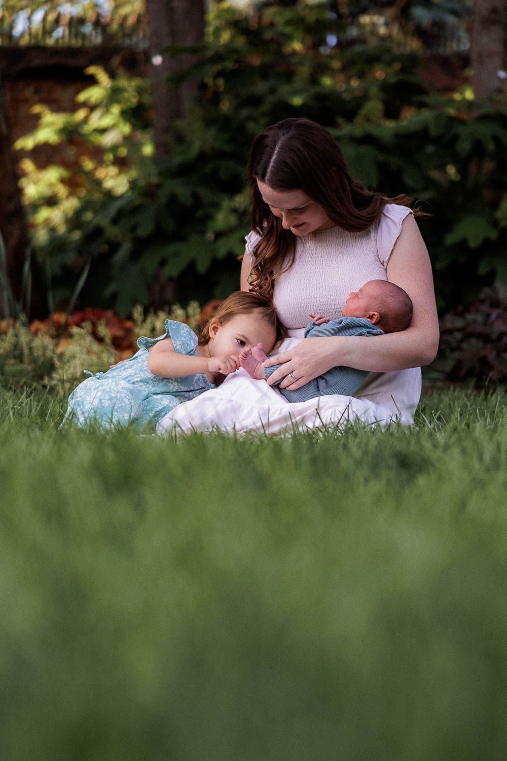 Mother and two children during spring outdoor newborn session in green grass at Historic Smithville Park in Eastampton, NJ