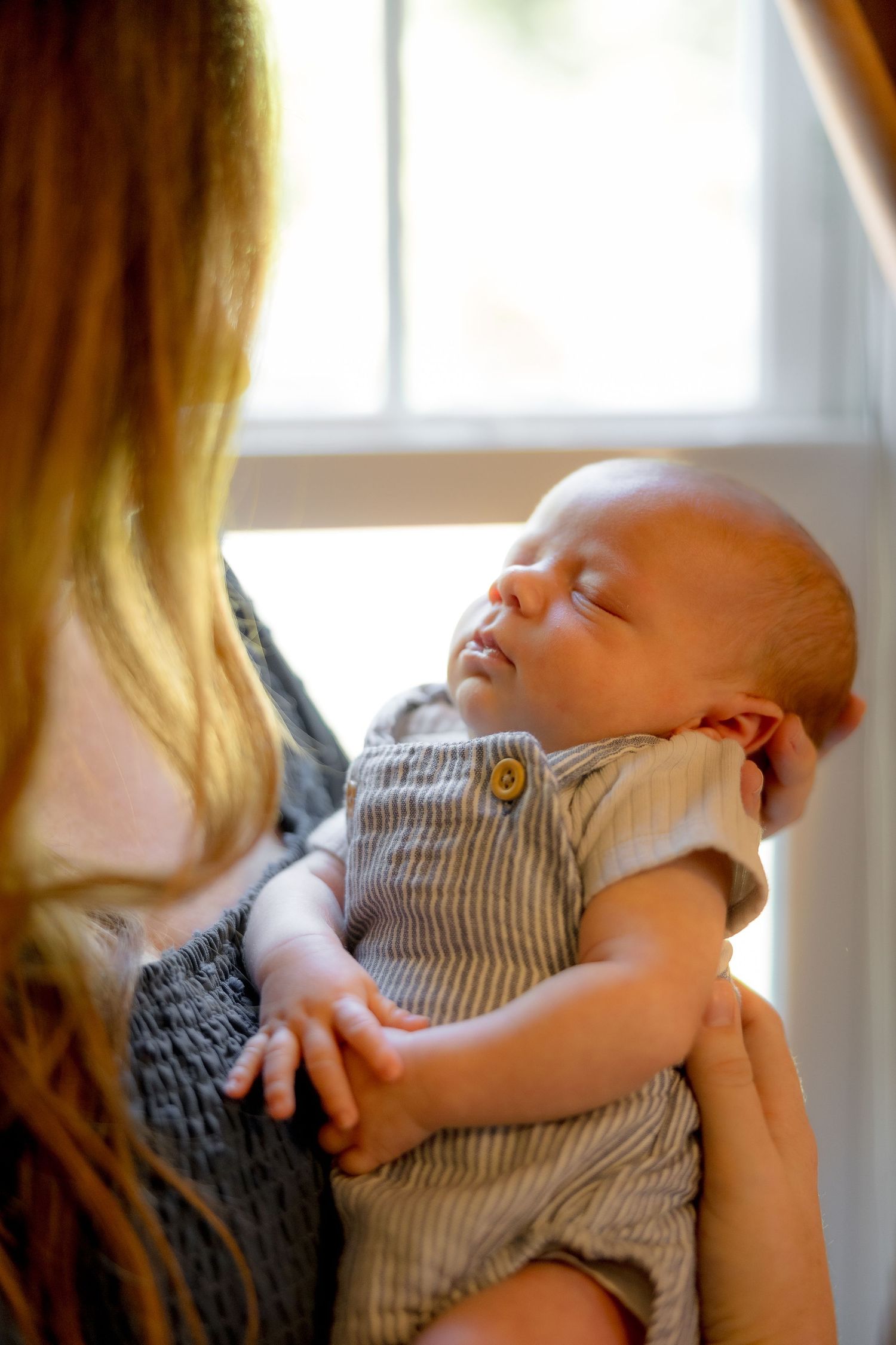 Sleeping newborn held by mother during lifestyle newborn photo session in Mercer County, New Jersey, by Rego Photography