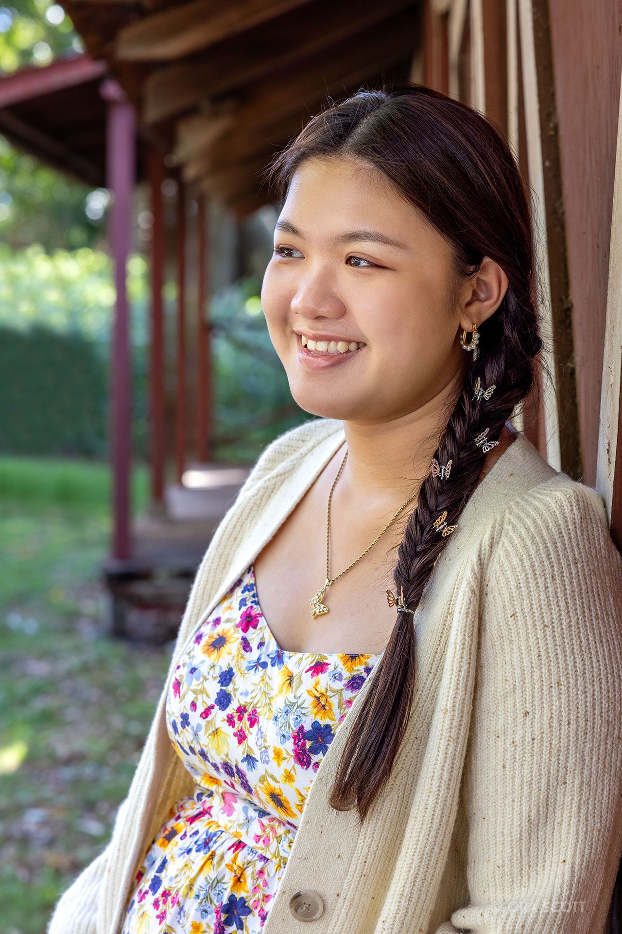senior girl smiling and wearing a floral print summer dress and beige cardigan at her senior photo session