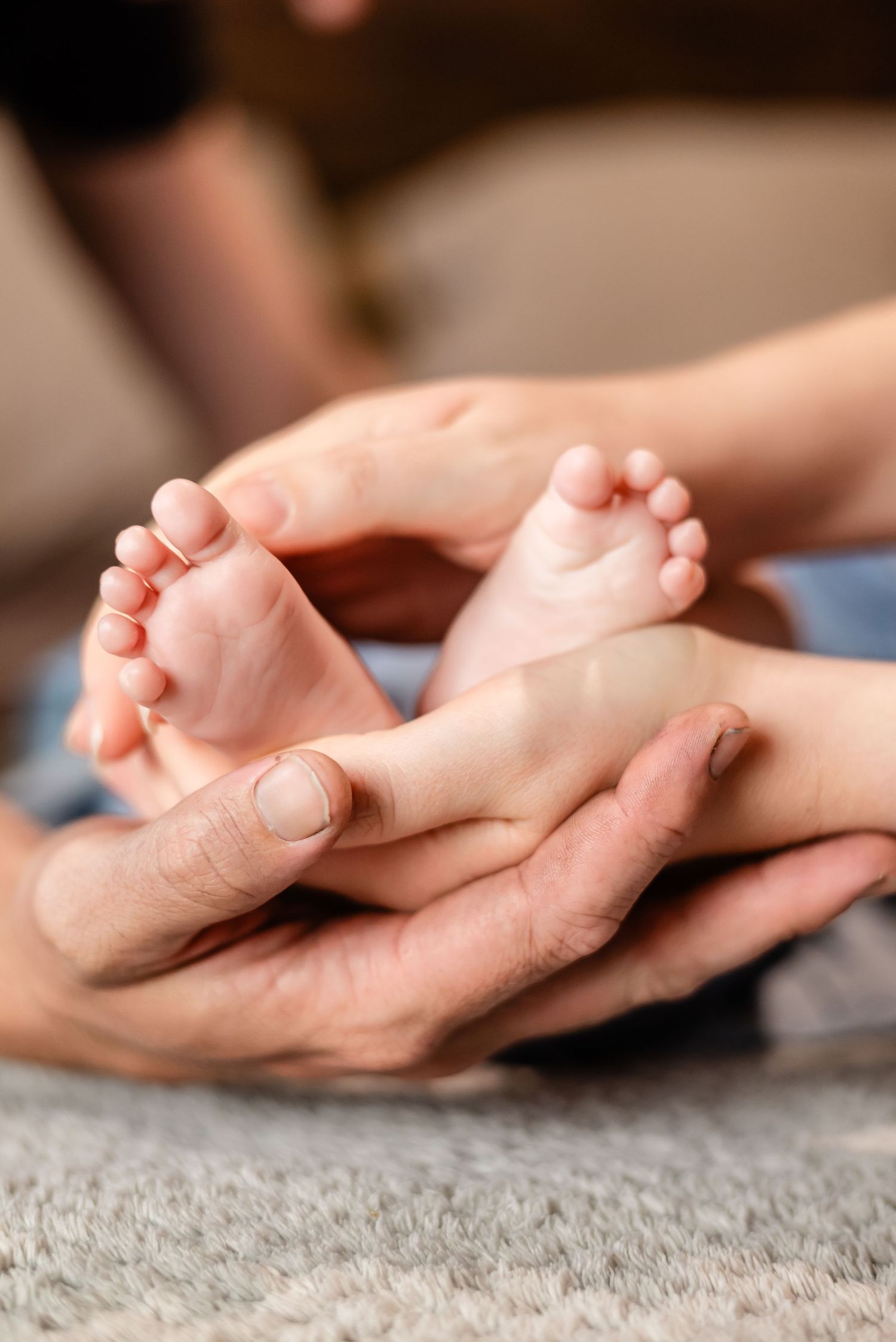 Close-up of tiny baby feet cradled in gentle hands.