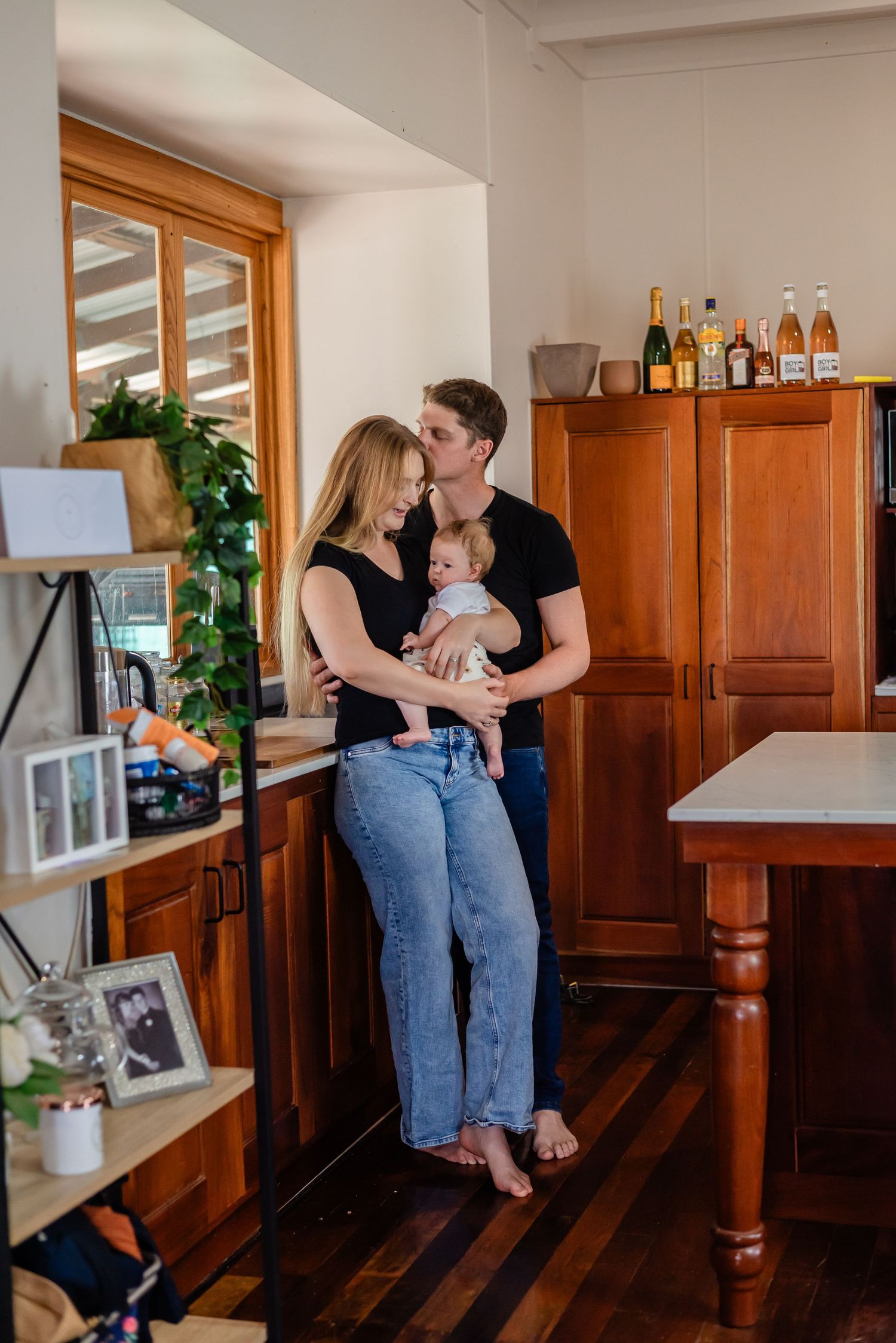 A romantic moment shared in a home interior with wooden floors and cabinet.