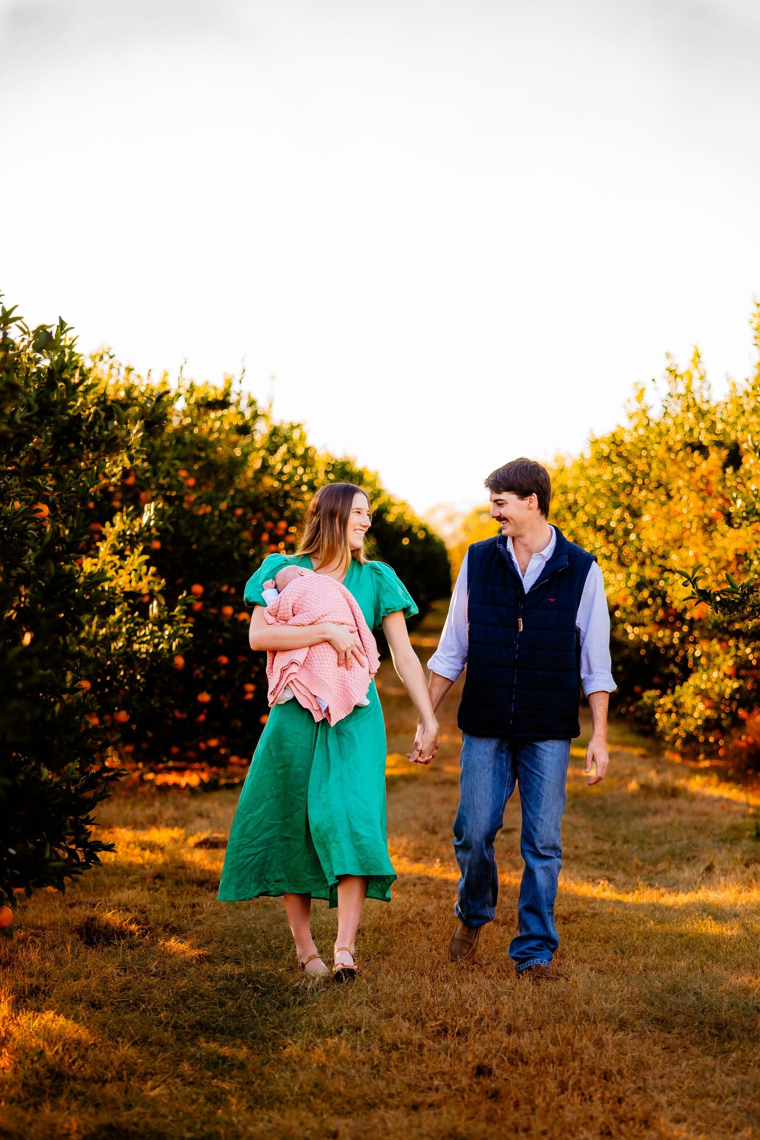 Couple walking together through an autumn orange grove at sunset in a romantic outdoor setting.