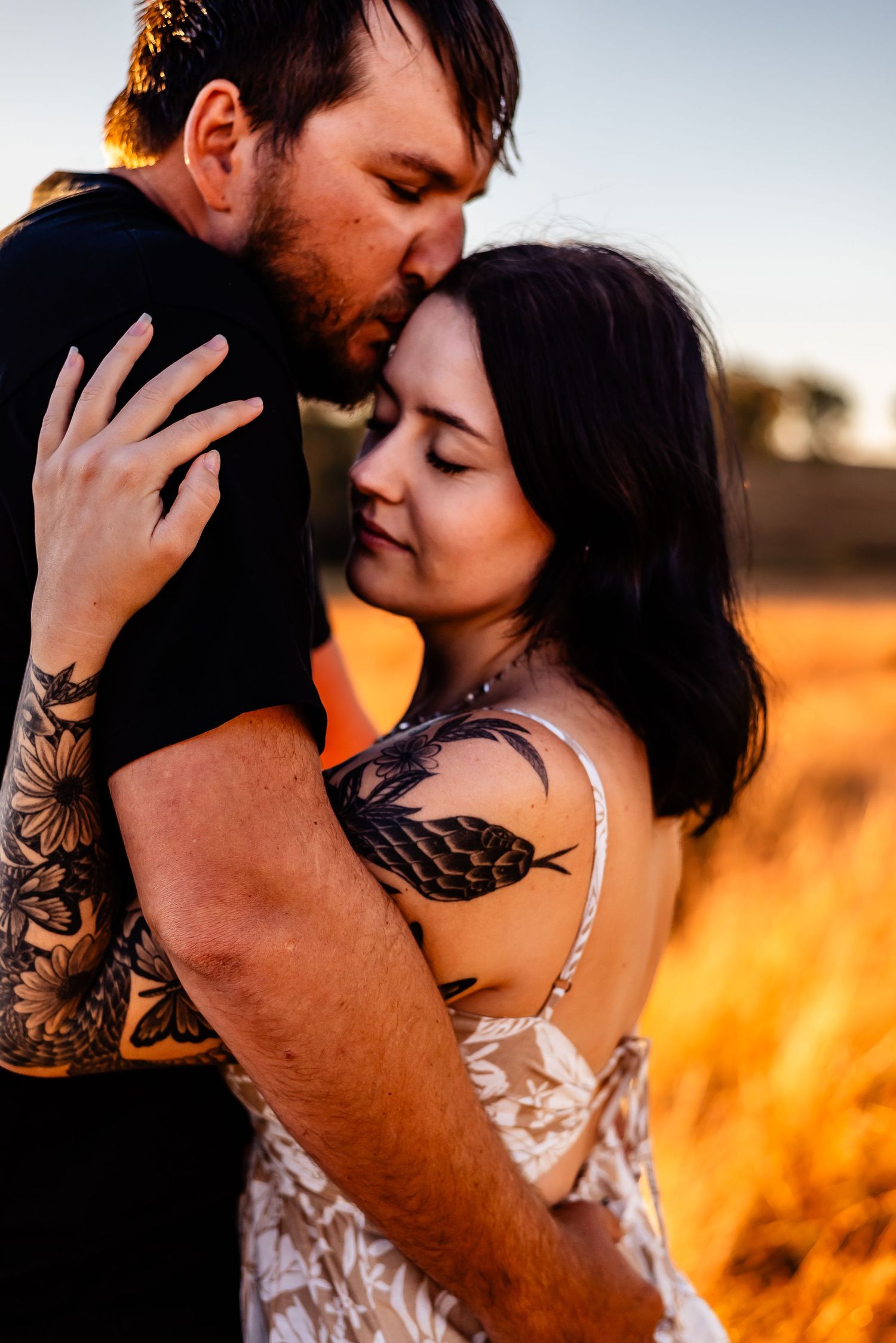 Romantic couple embracing in golden wheat field at sunset.