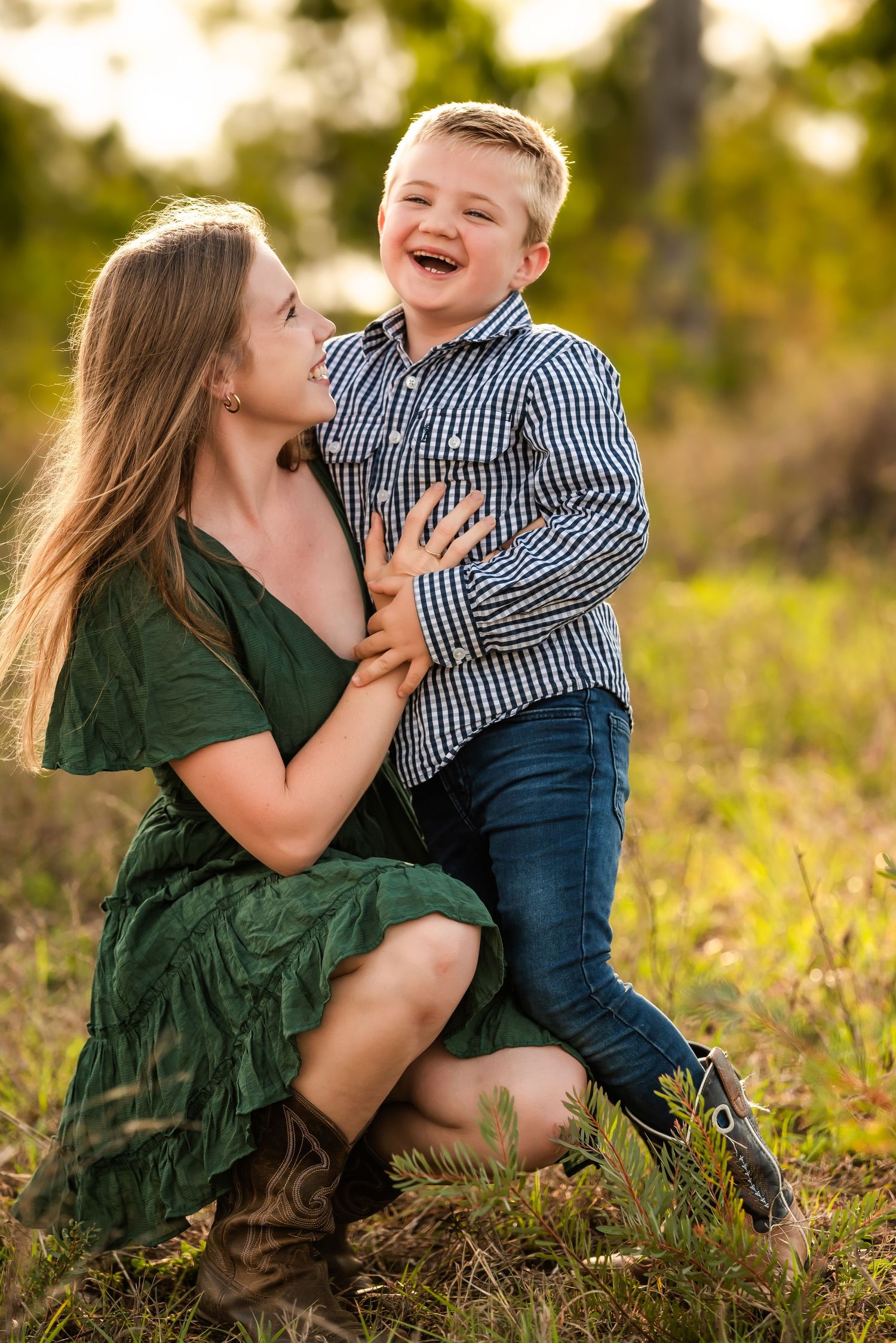 Playful family moment captured on grassy hillside during golden hour.