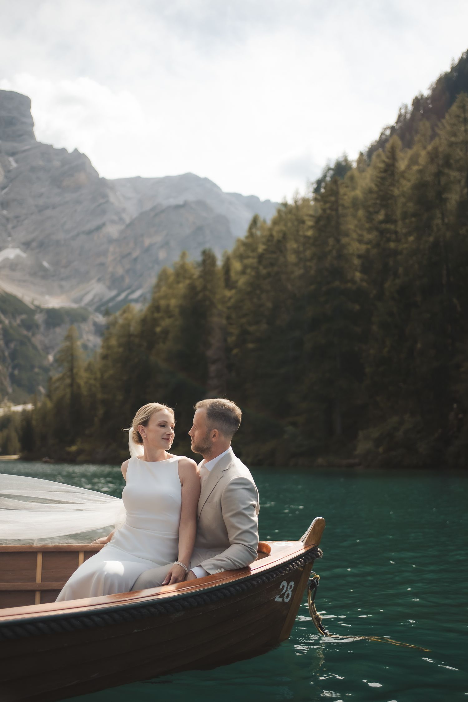 Beautiful sunset reflection of a bride and groom looking at each other on a wooden boat during their romantic Dolomites elopement.