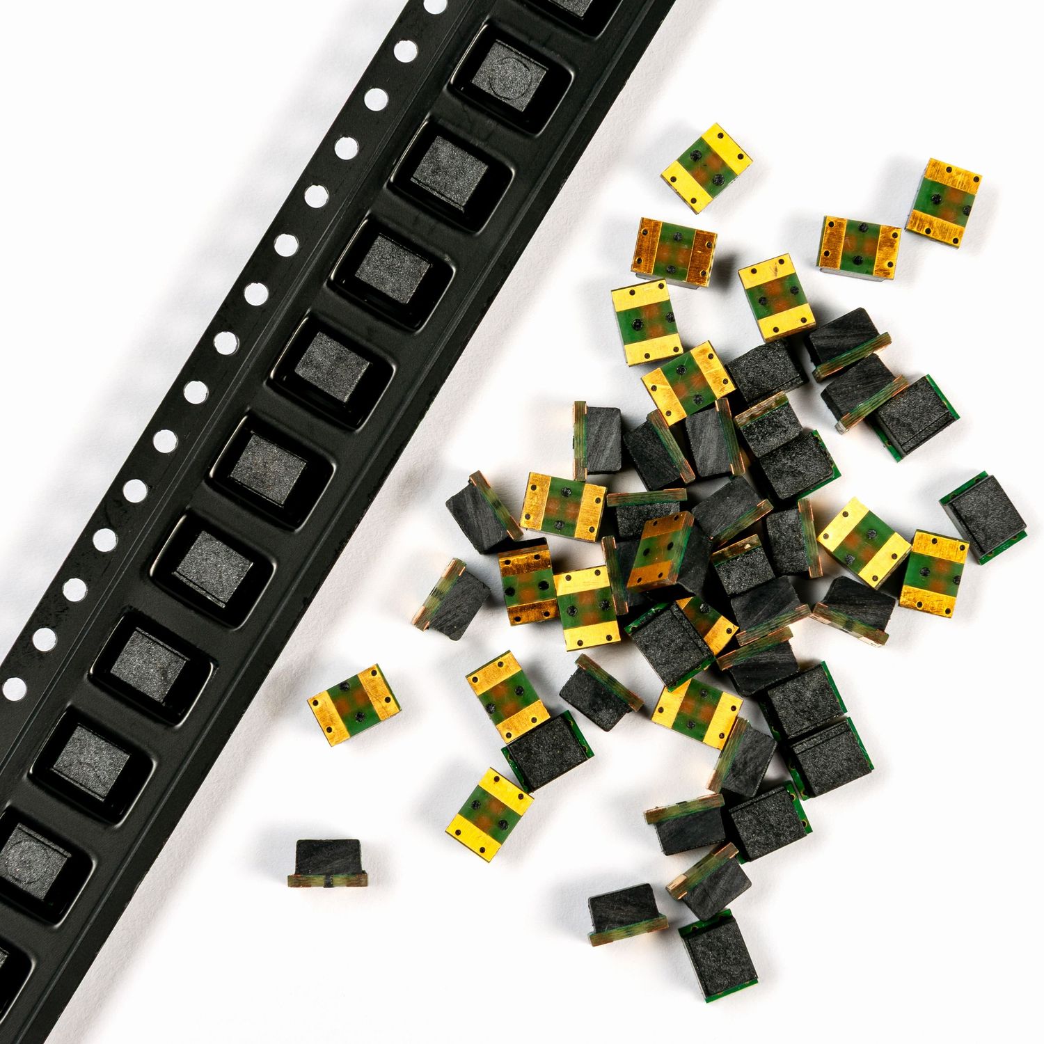 Strip of square fuses next to a pile of loose fuses on a white background.by stonehouse photographic.