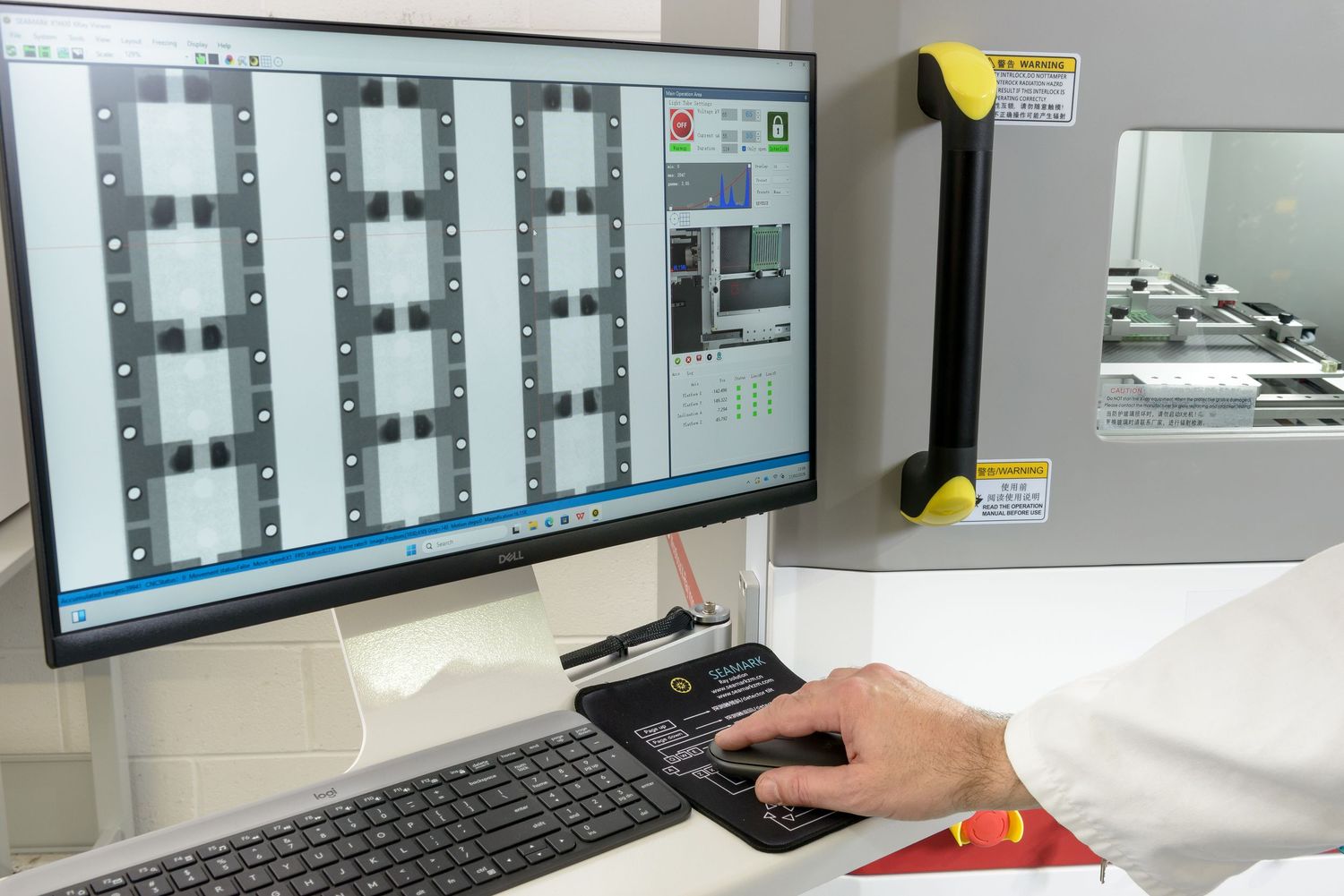 Small parts x-ray machine showing screen and x-ray chamber with hand operating the computer.by stonehouse photographic.