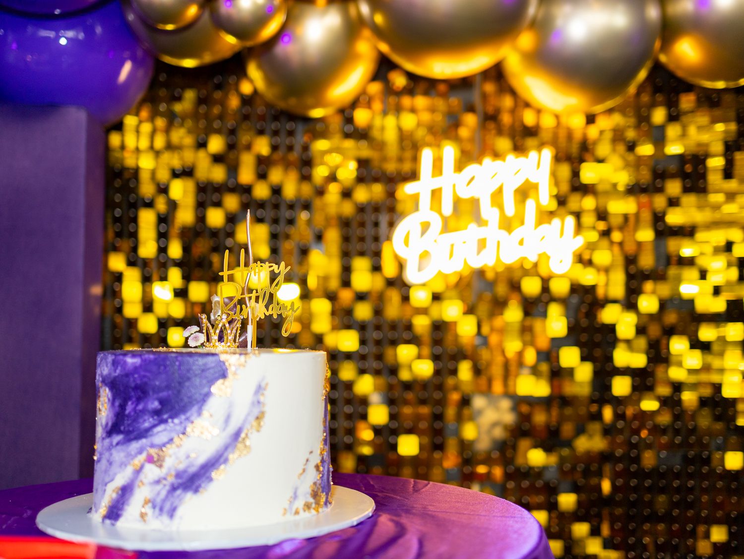 Celebration backdrop with gold bokeh lights and elegant white birthday cake.