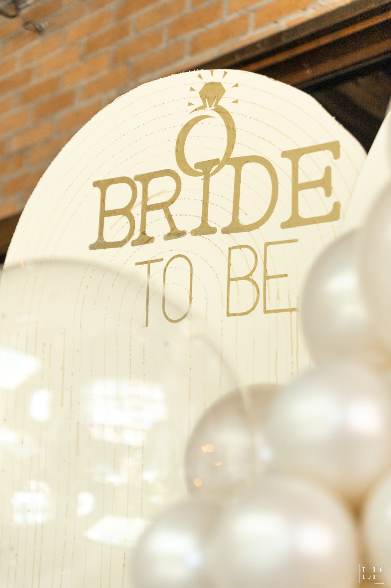 Decorative 'Bride To Be' text signs with diamond ring icons displayed against a brick wall.