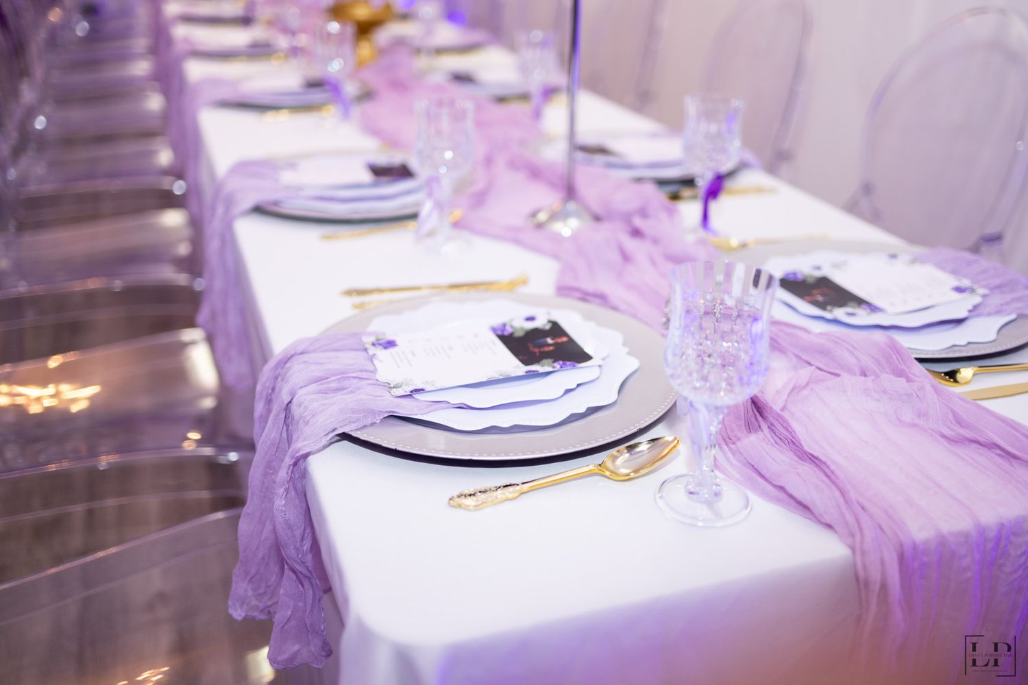 Elegant table settings with purple lighting and white linens at a formal event.