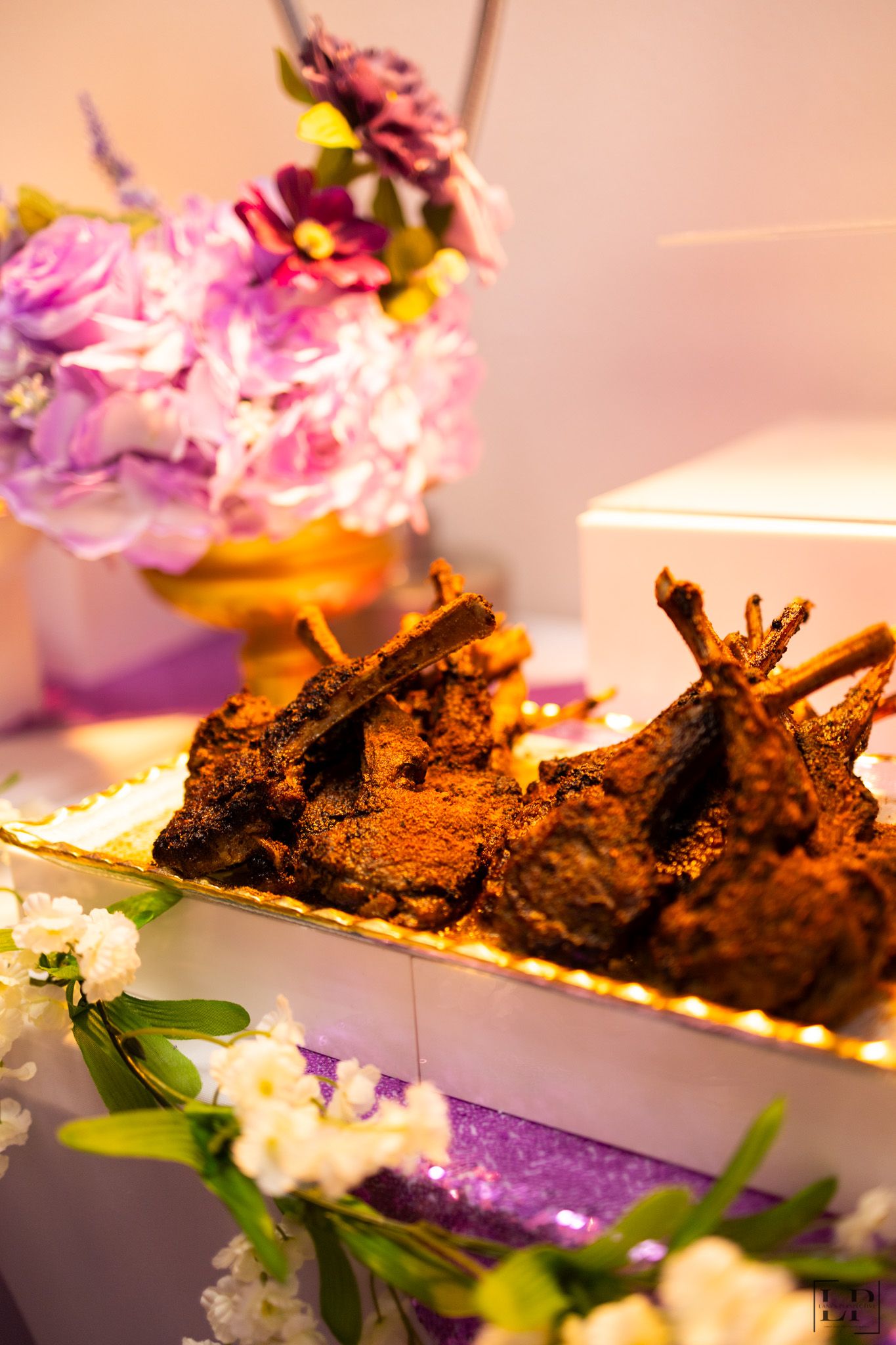 Elegant plated dish with grilled meat and delicate floral garnishes in warm lighting.