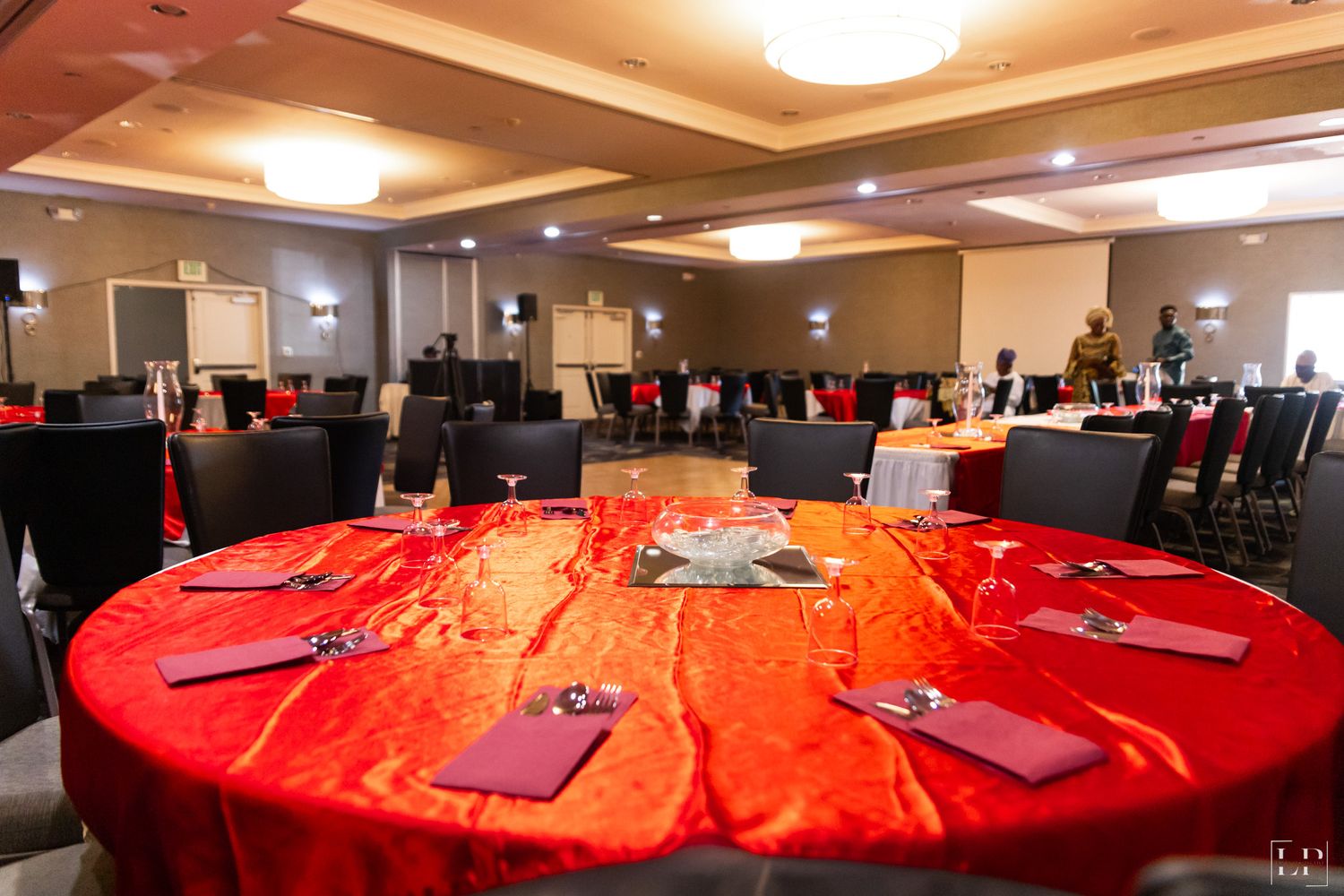Conference room setup with round tables covered in bright red tablecloths.