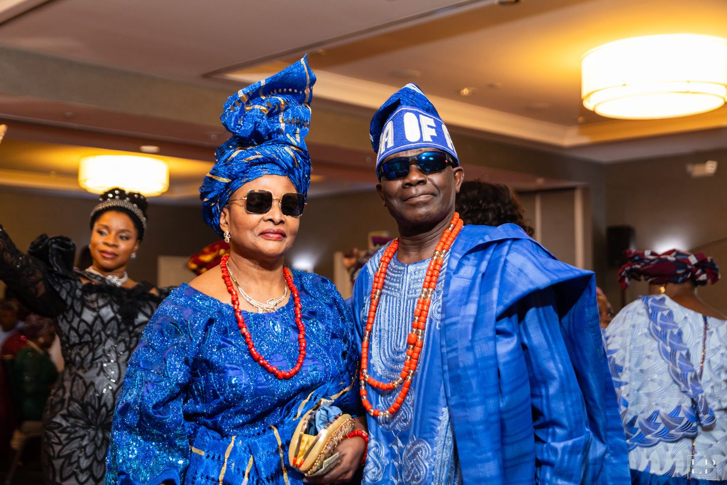 Attendees in vibrant blue traditional Nigerian attire celebrate at a formal event.