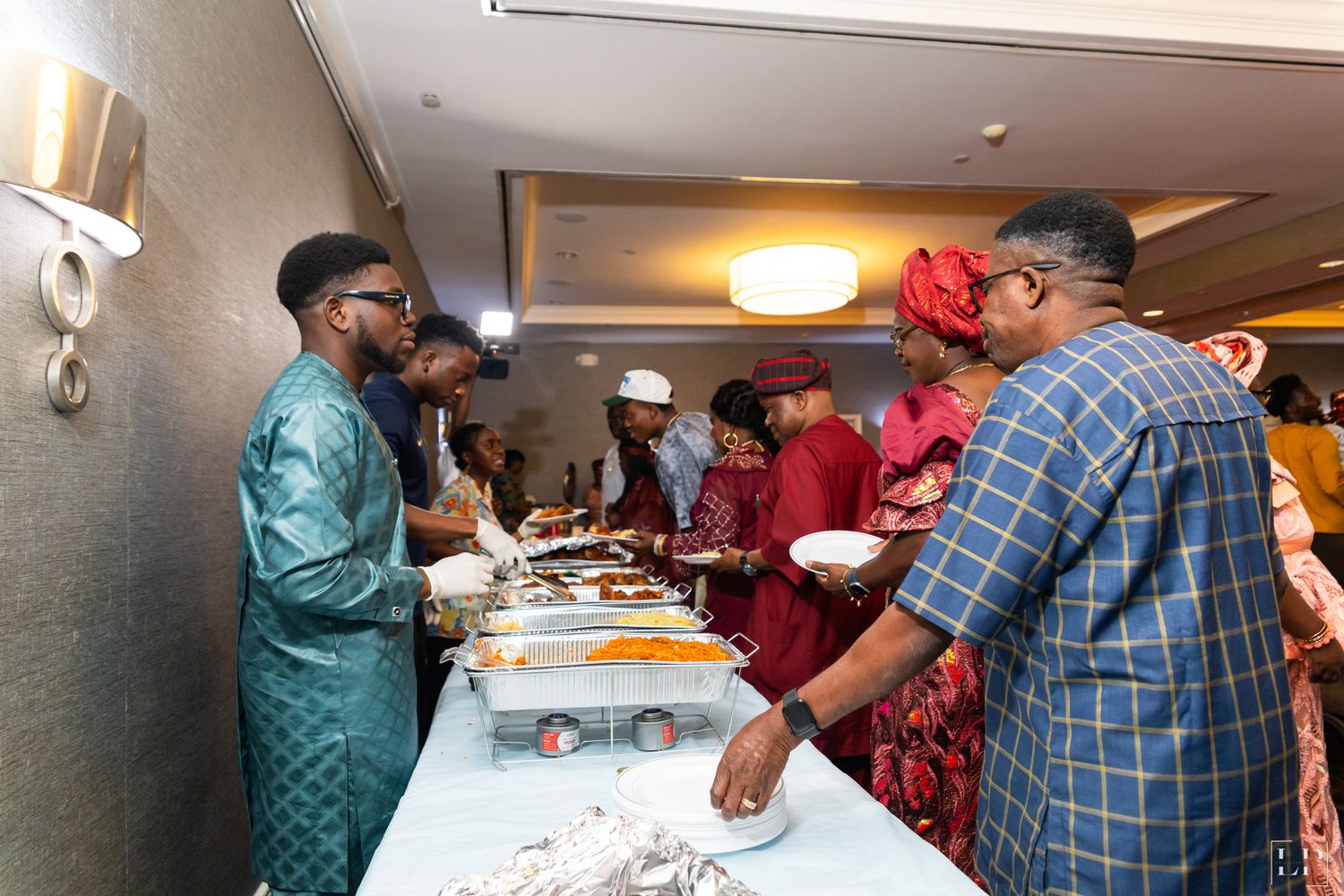 Guests serving themselves at a formal buffet line in traditional African attire.