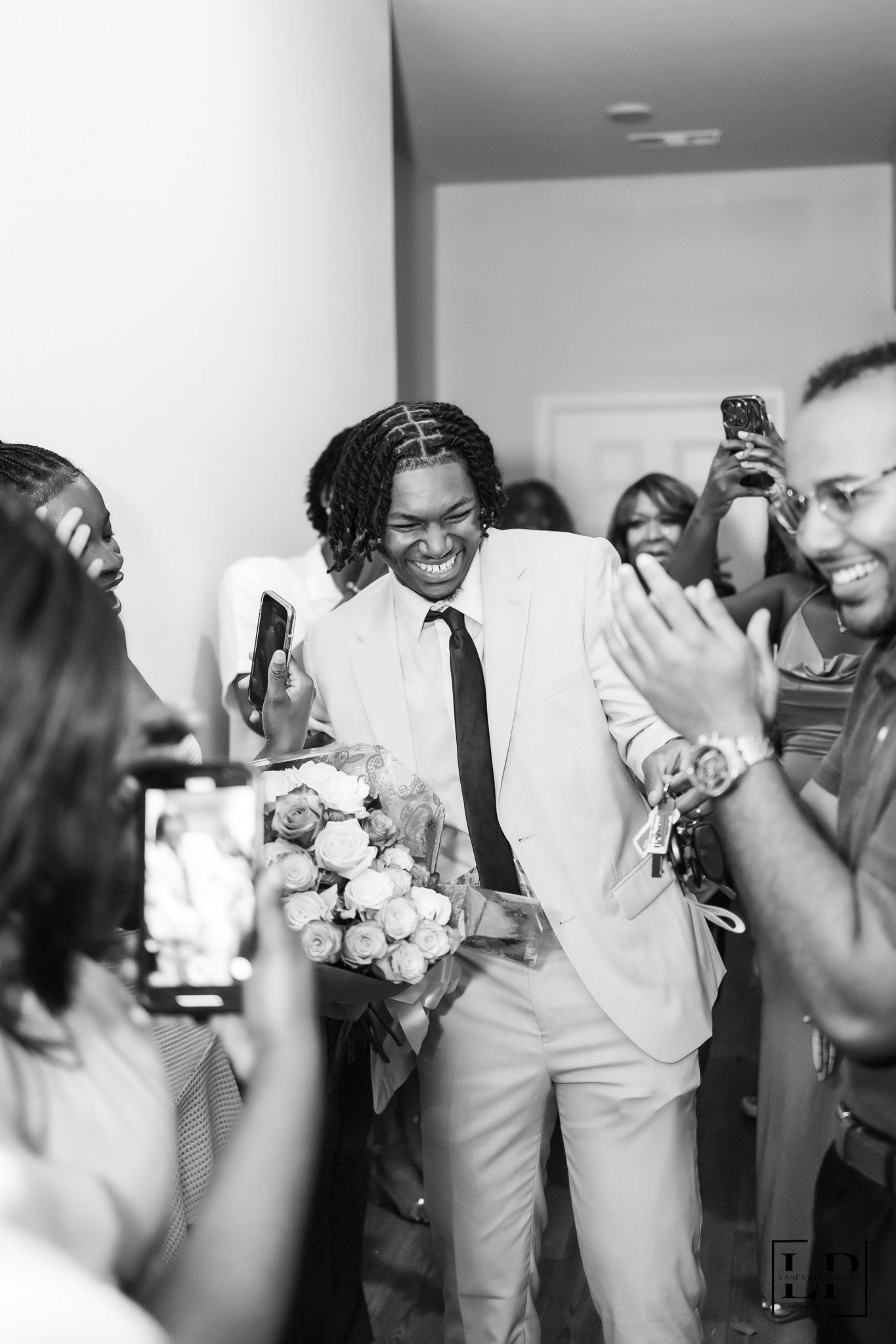 Black and white candid celebration photo with guests taking pictures on phones.