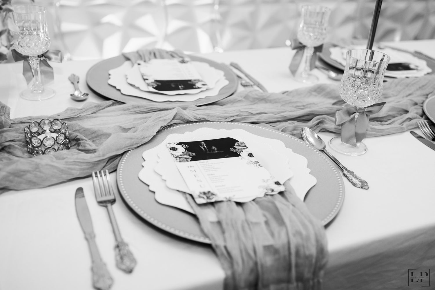 Formal table setting with white linens, crystal glassware and silver cutlery.
