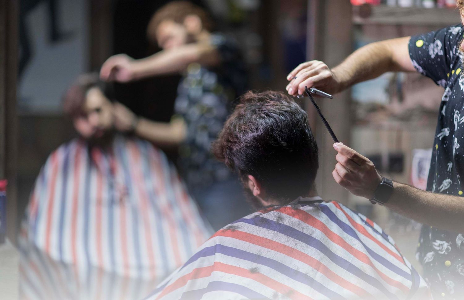 Close-up of haircut in progress at barbershop with striped cape visible.