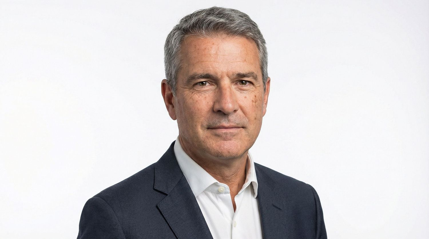 Professional headshot of executive in business attire against light background.