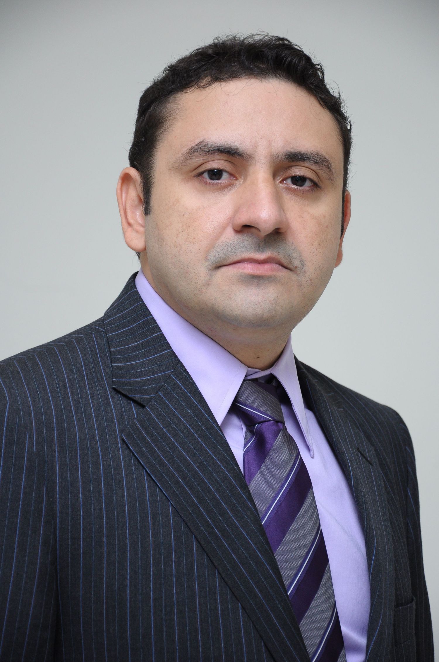 Professional portrait of businessman wearing pinstripe suit and purple tie.