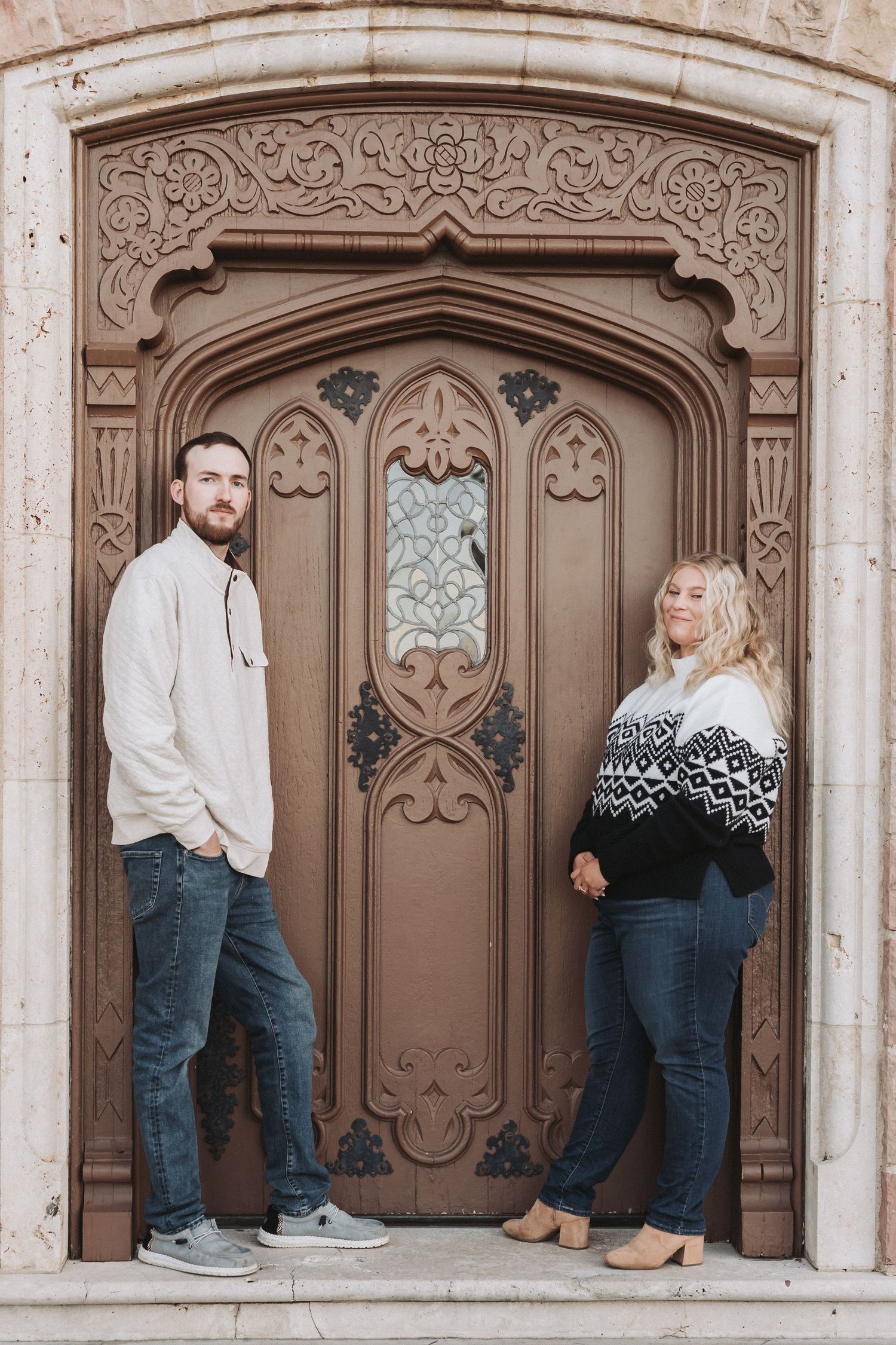A couple poses in three different arrangements against an ornate stone archway with decorative carved details.