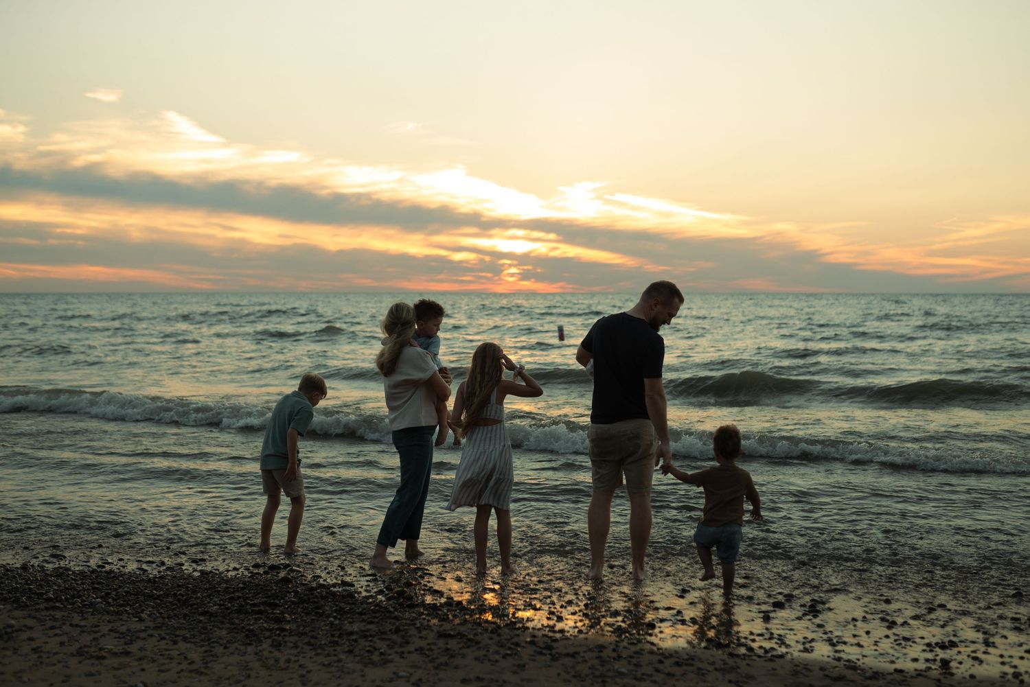 family putting feet in water at the beach