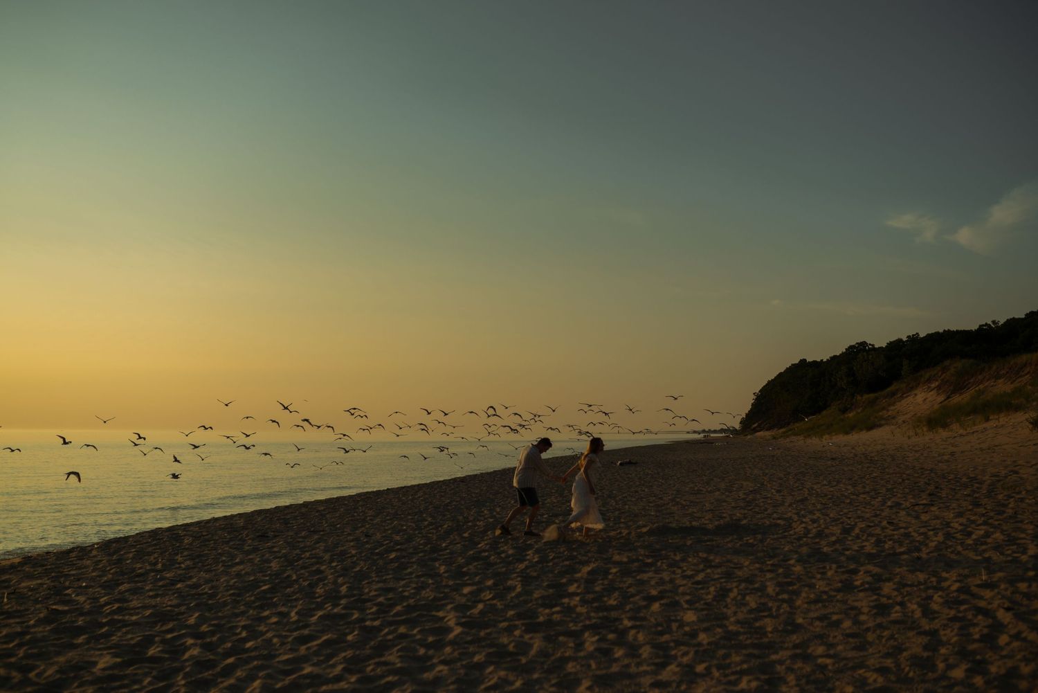 couple running with seagulls at the beach