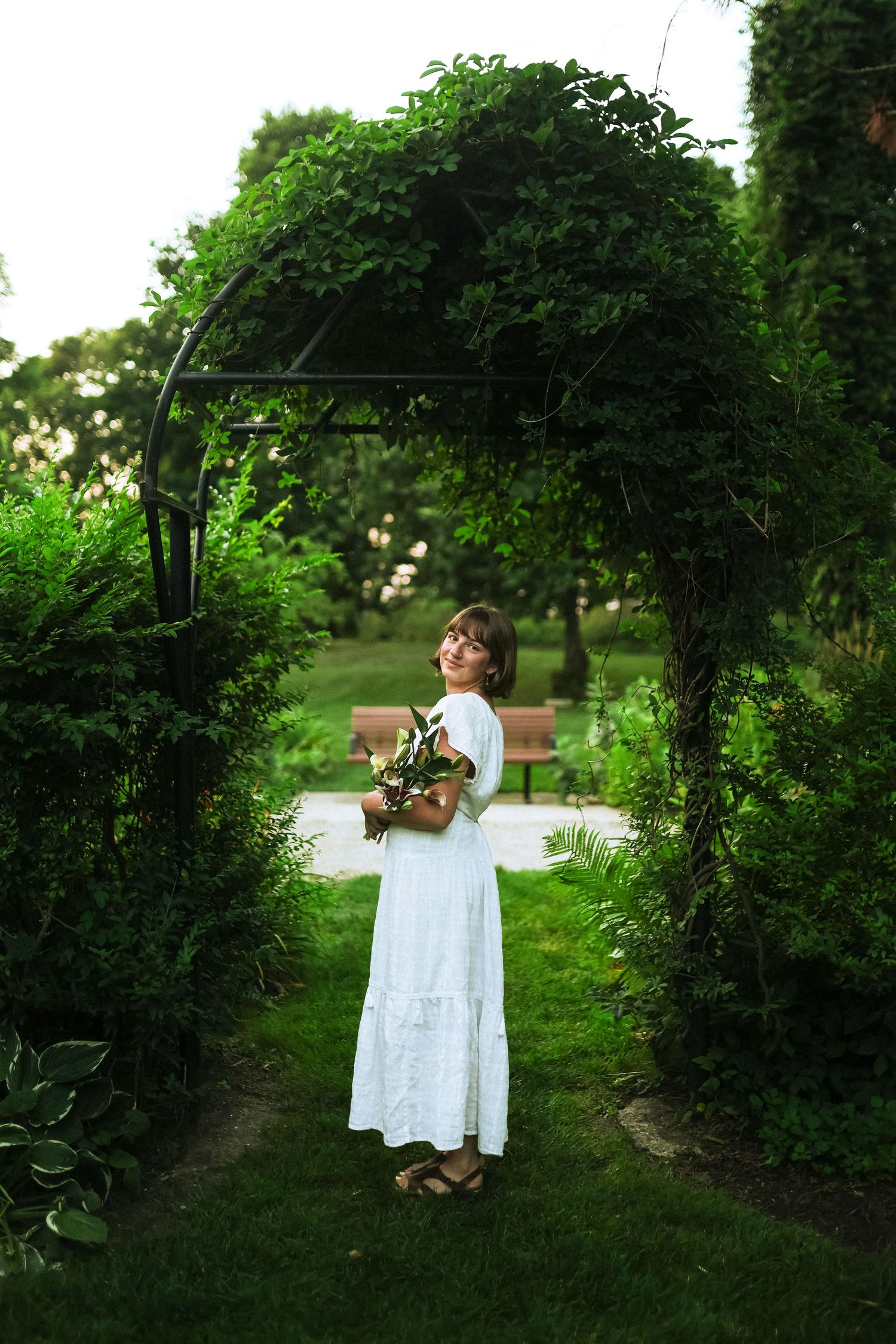 Kennedy posing underneath arch with bouquet or lilies