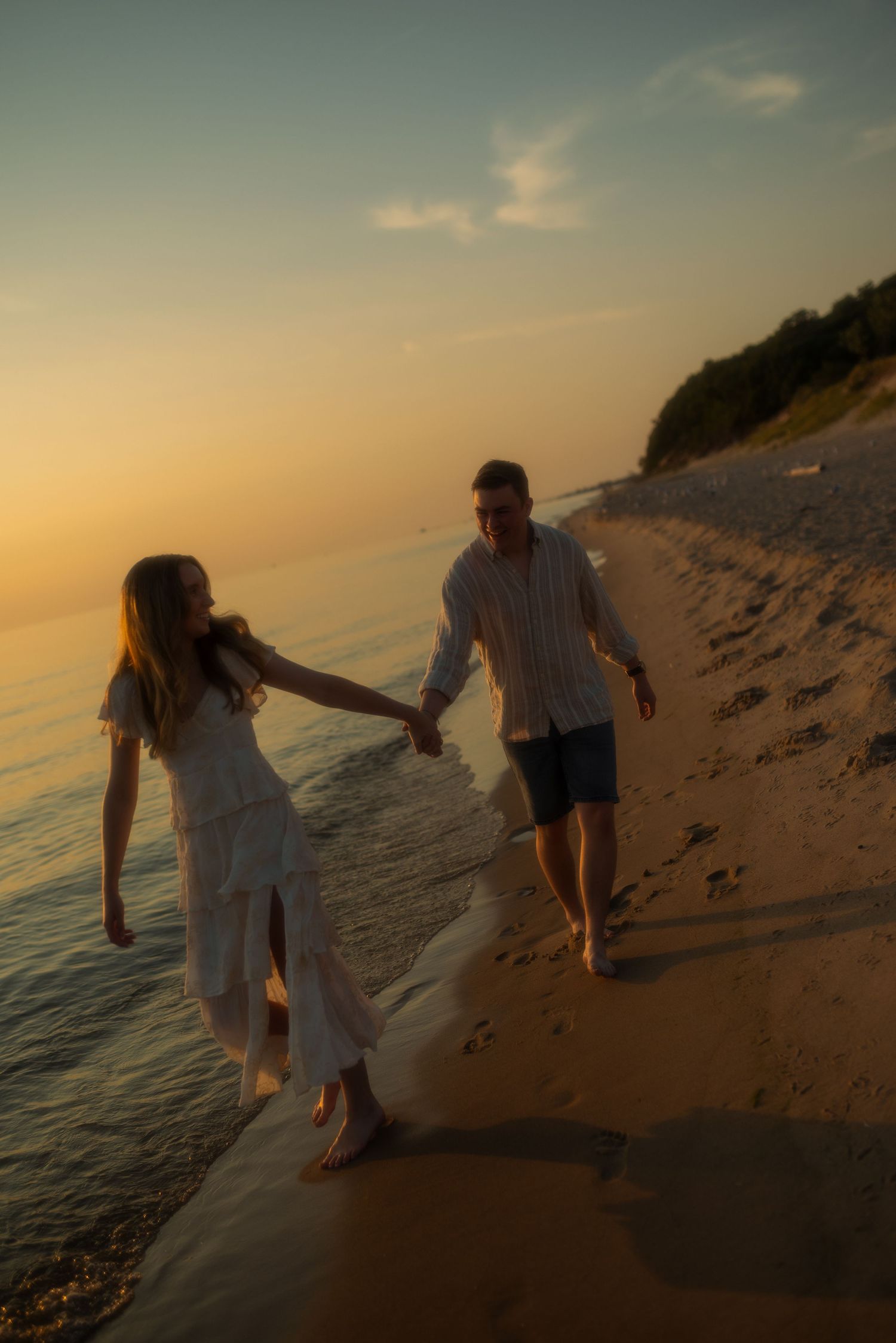 newly engaged couple holding hands on the beach