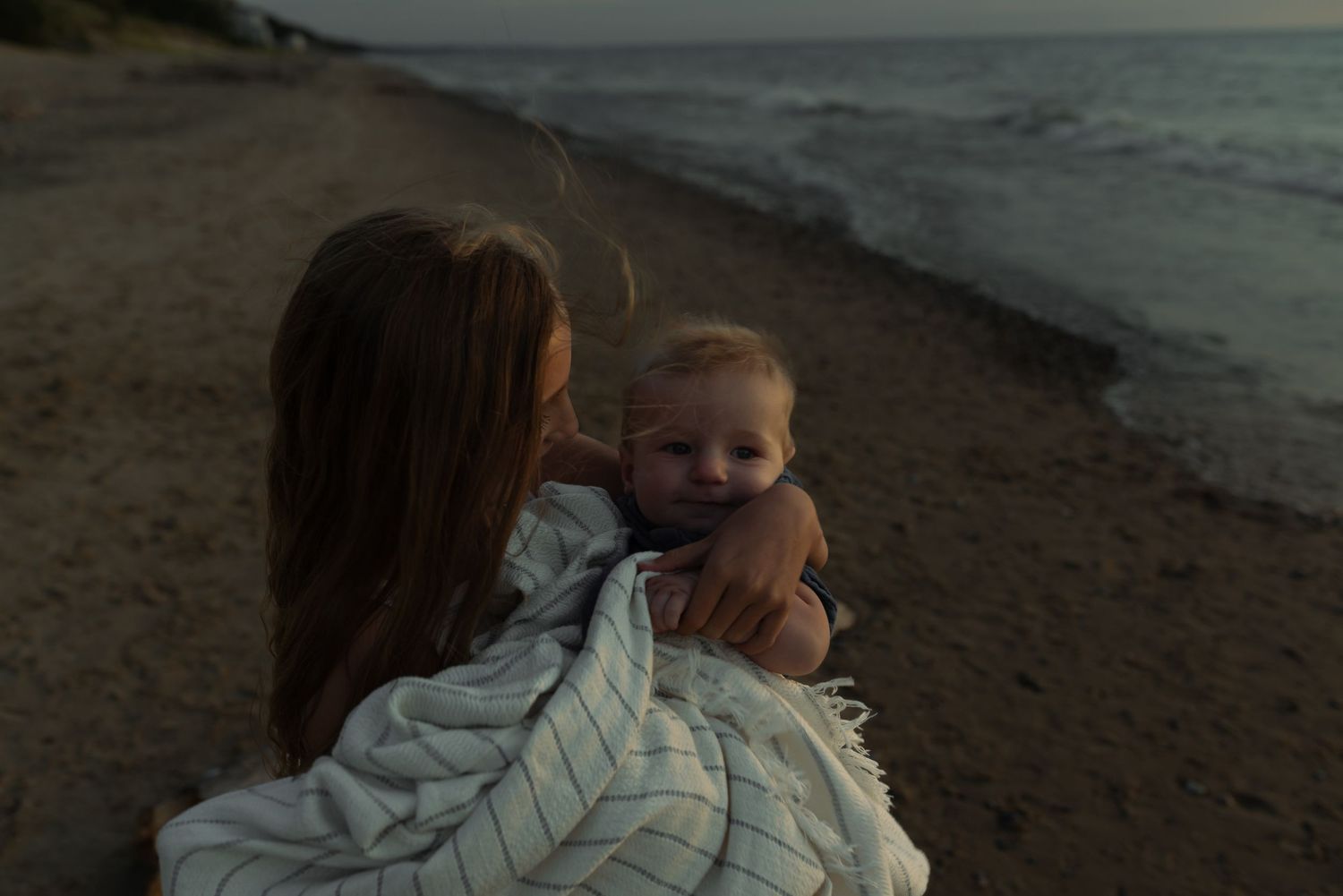 girl holding her little brother in a blanket