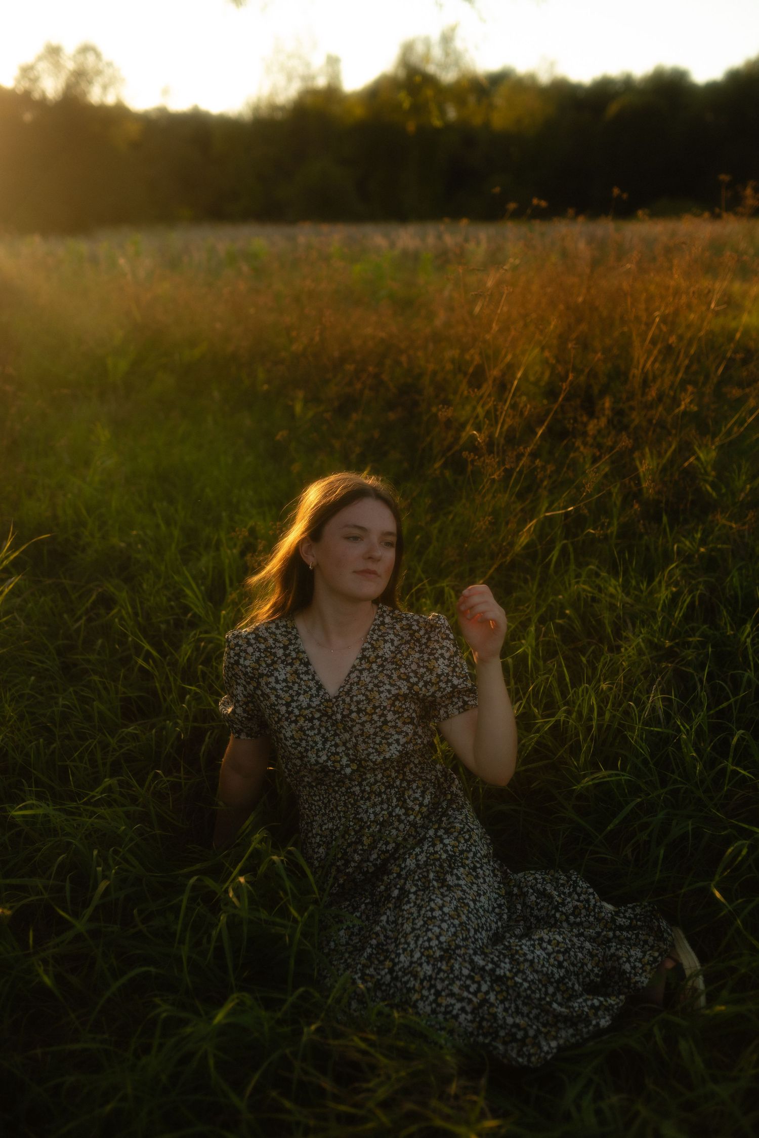 Girl sitting in the grass at sunset