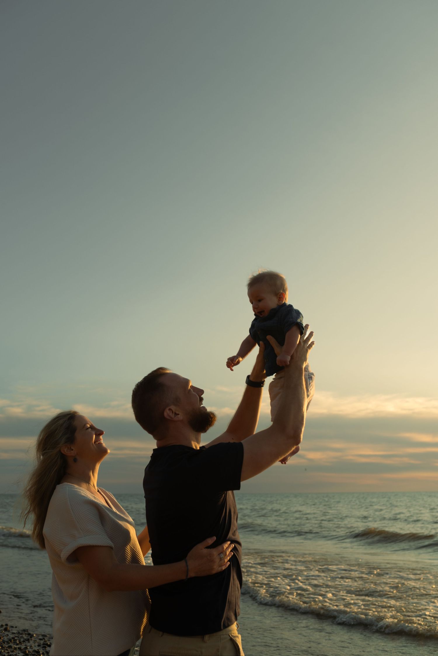 dad throwing son in the air as mom watches