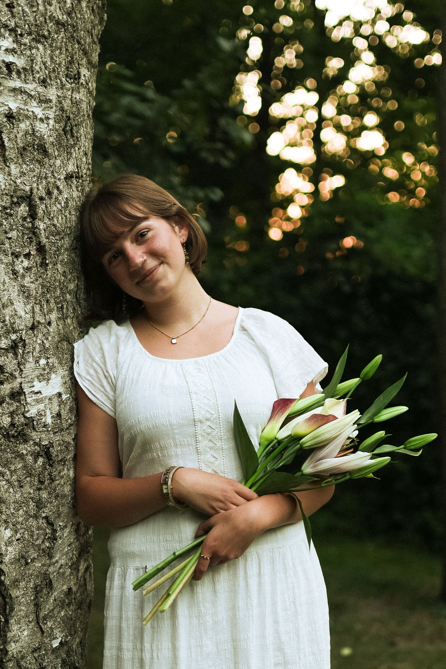 Kennedy leaning against tree with bouquet of lilies