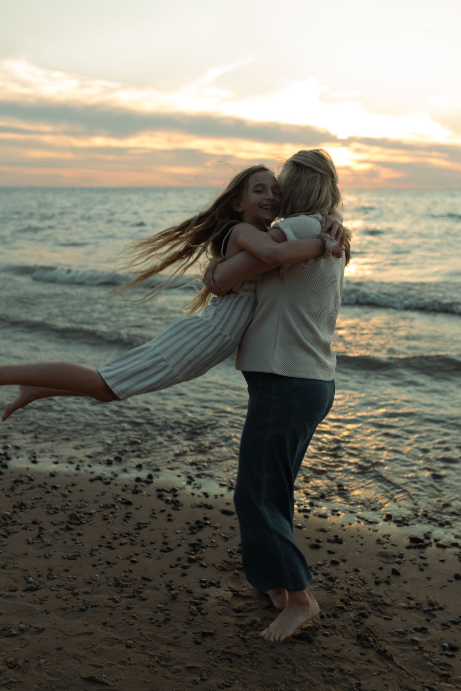mom swinging around daughter at the beach