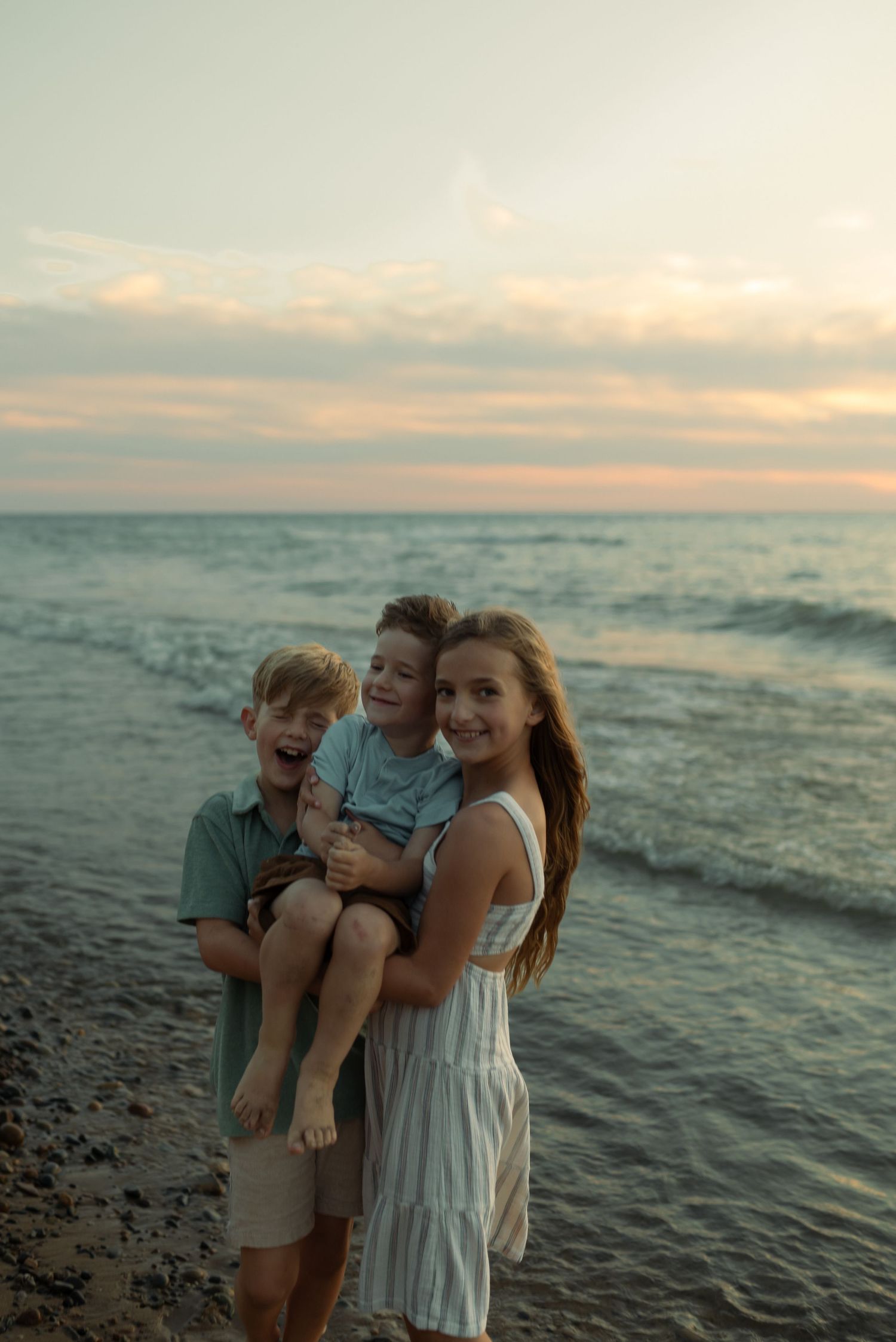 siblings holding little brother at the beach