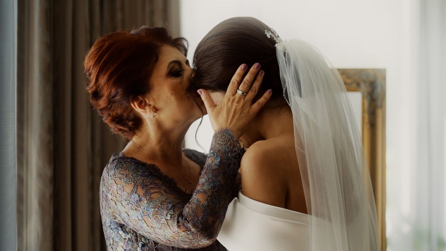 Mother kissing ger daughter on her wedding day