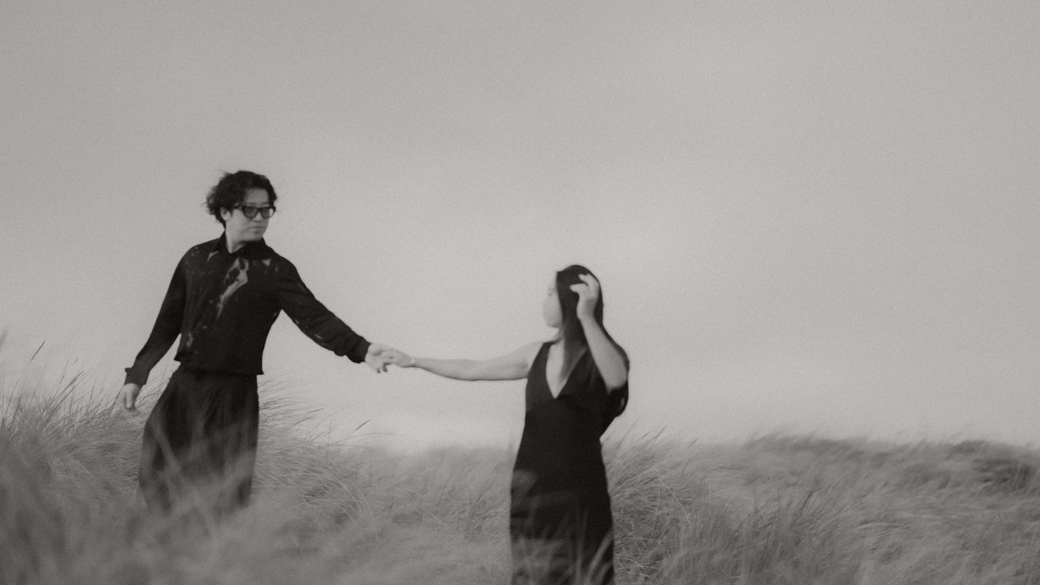 A series of black and white photos showing people walking and dancing along a beach shoreline.