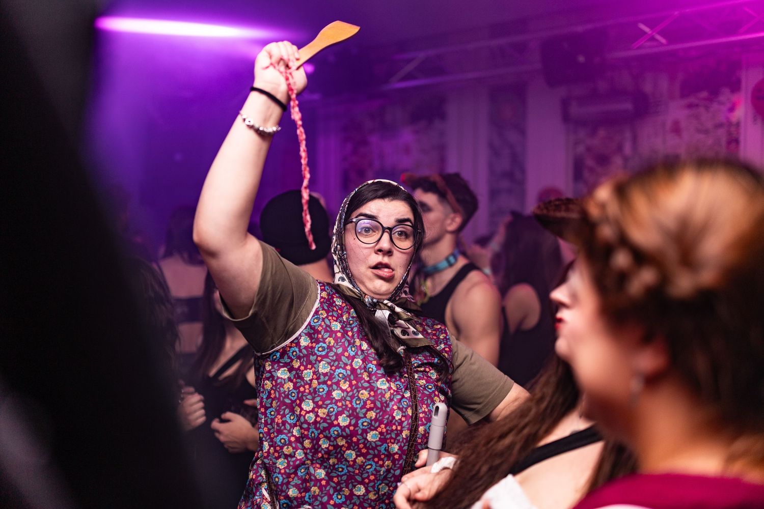 People dancing and enjoying themselves at a nightclub with purple lighting and energetic atmosphere.