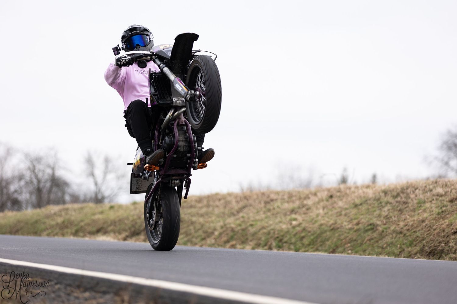 Motorcycle performing dramatic wheelie stunt on empty road.