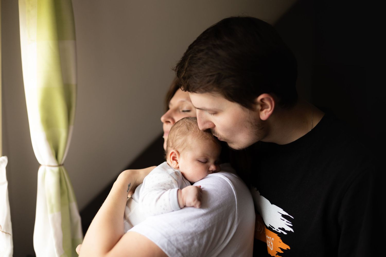 A tender moment shared between parent and baby in soft window light.