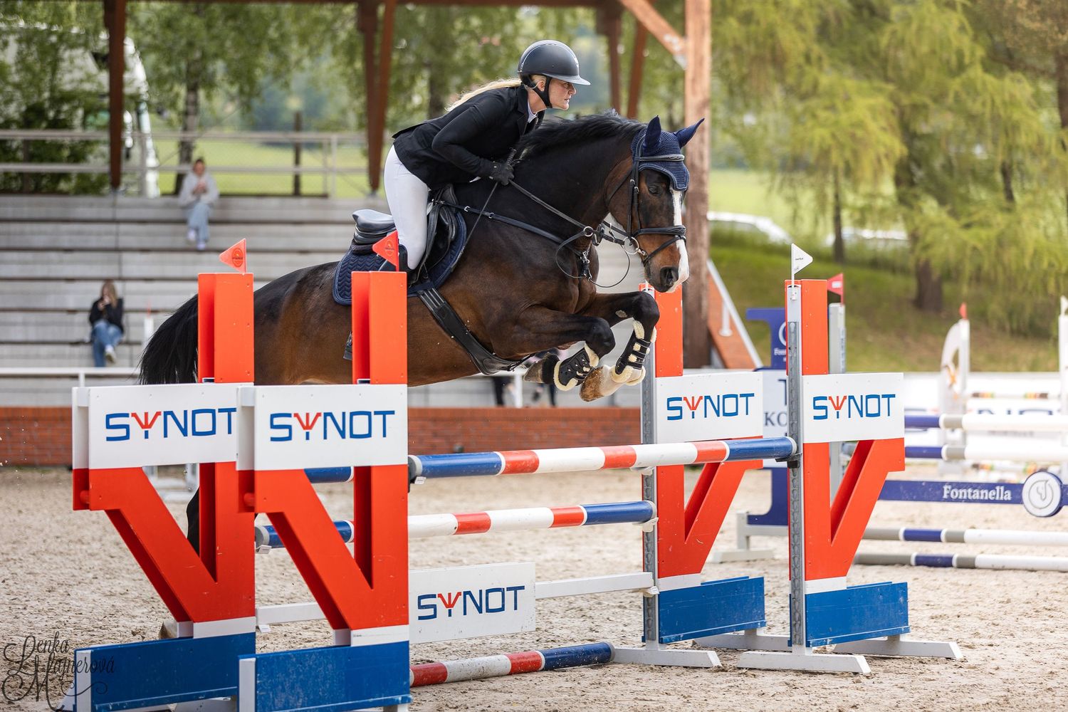 Horse and rider navigate through a series of colorful show jumping obstacles during an equestrian competition.