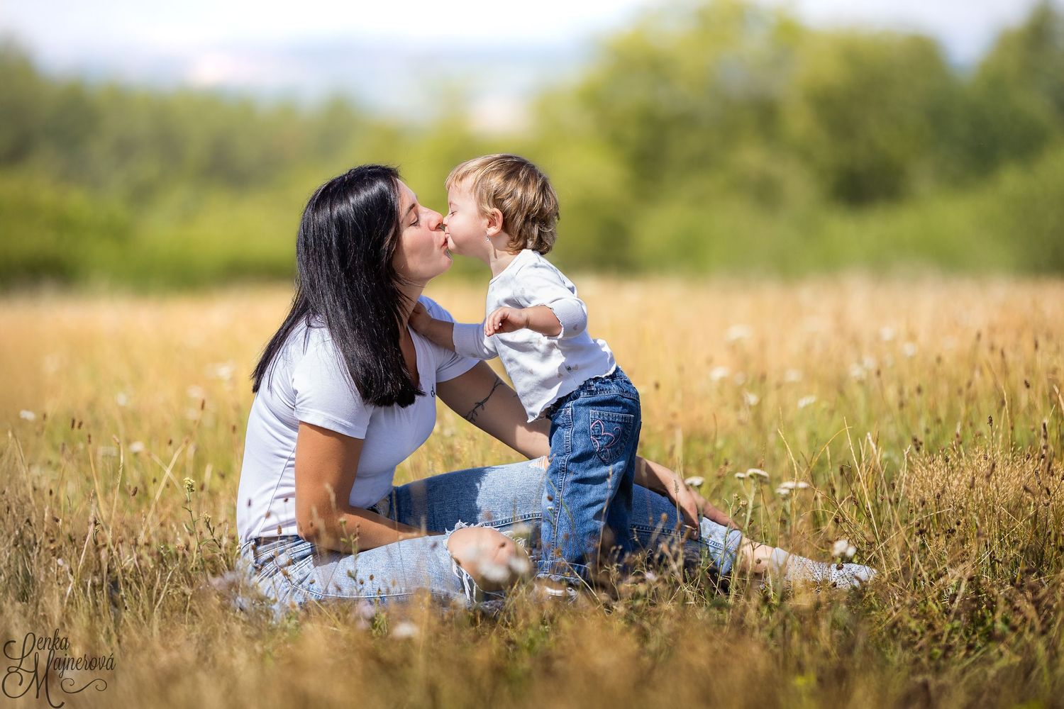 Tender family moment captured in a golden wheat field during sunset with soft natural lighting.