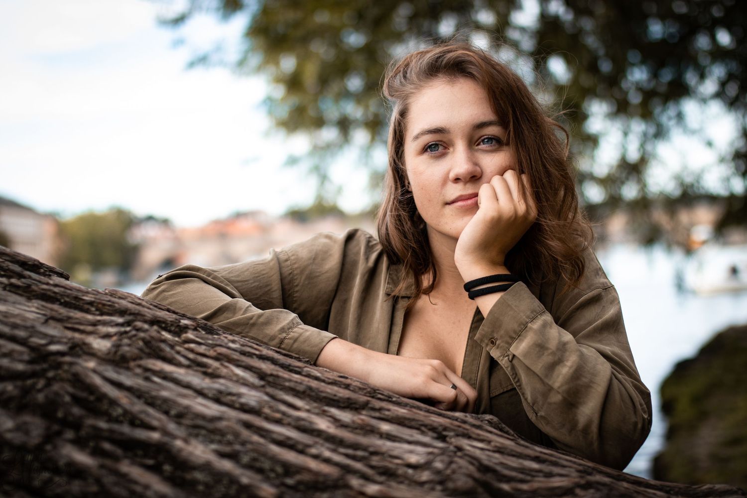 Natural outdoor portrait leaning on tree trunk in warm sunlight.