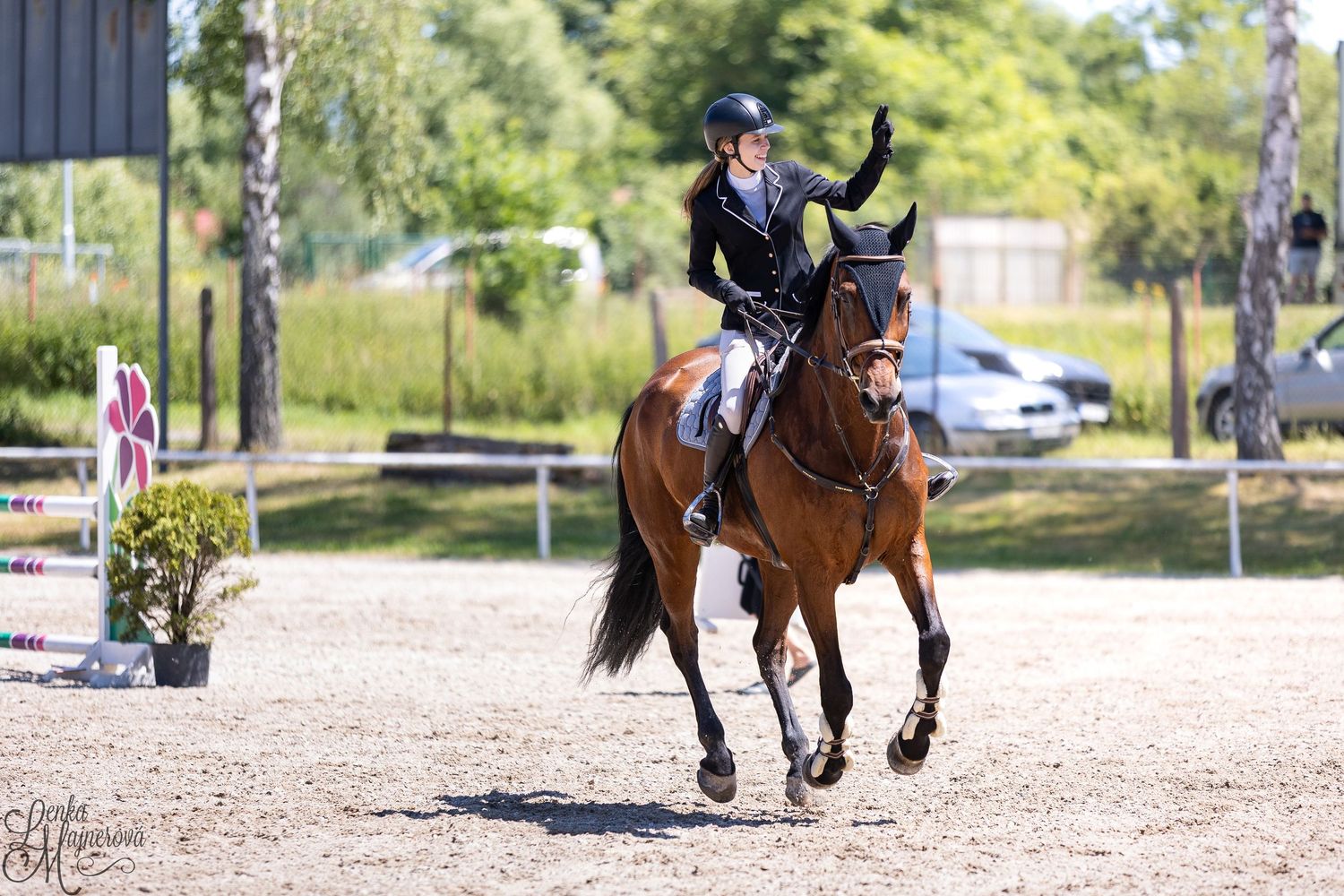 Equestrian riders compete in a dressage event on a sunny day at an outdoor arena.
