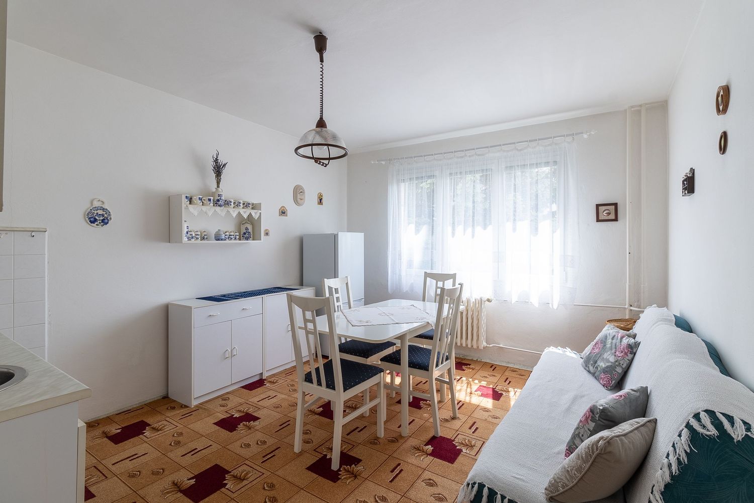 Cozy living room with white furniture, dining table and parquet flooring illuminated by natural light.